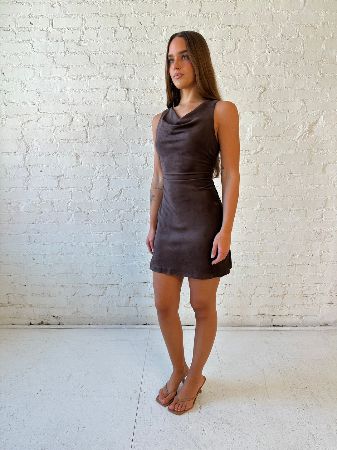 Woman wearing dark brown suede mini dress with high cowl neckline.