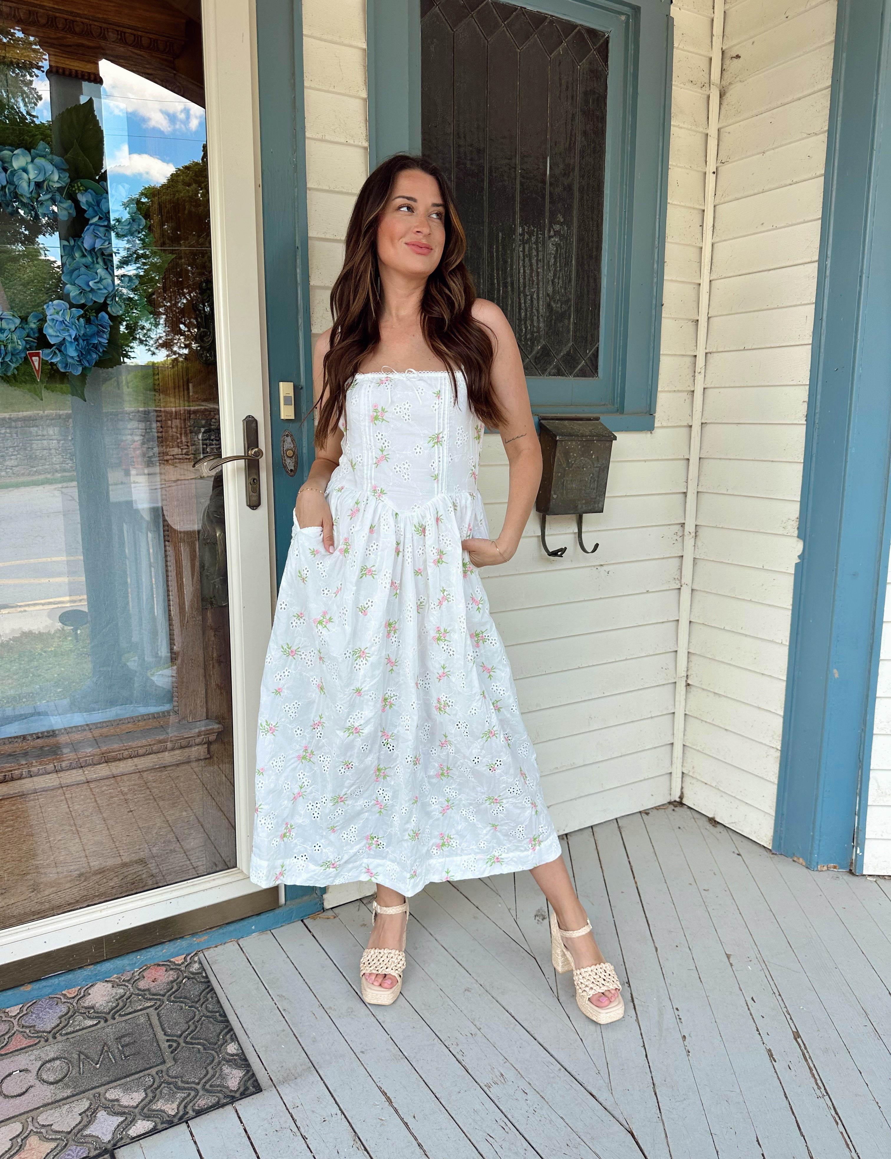 White midi dress with pink and green embroidery floral and functional pockets.