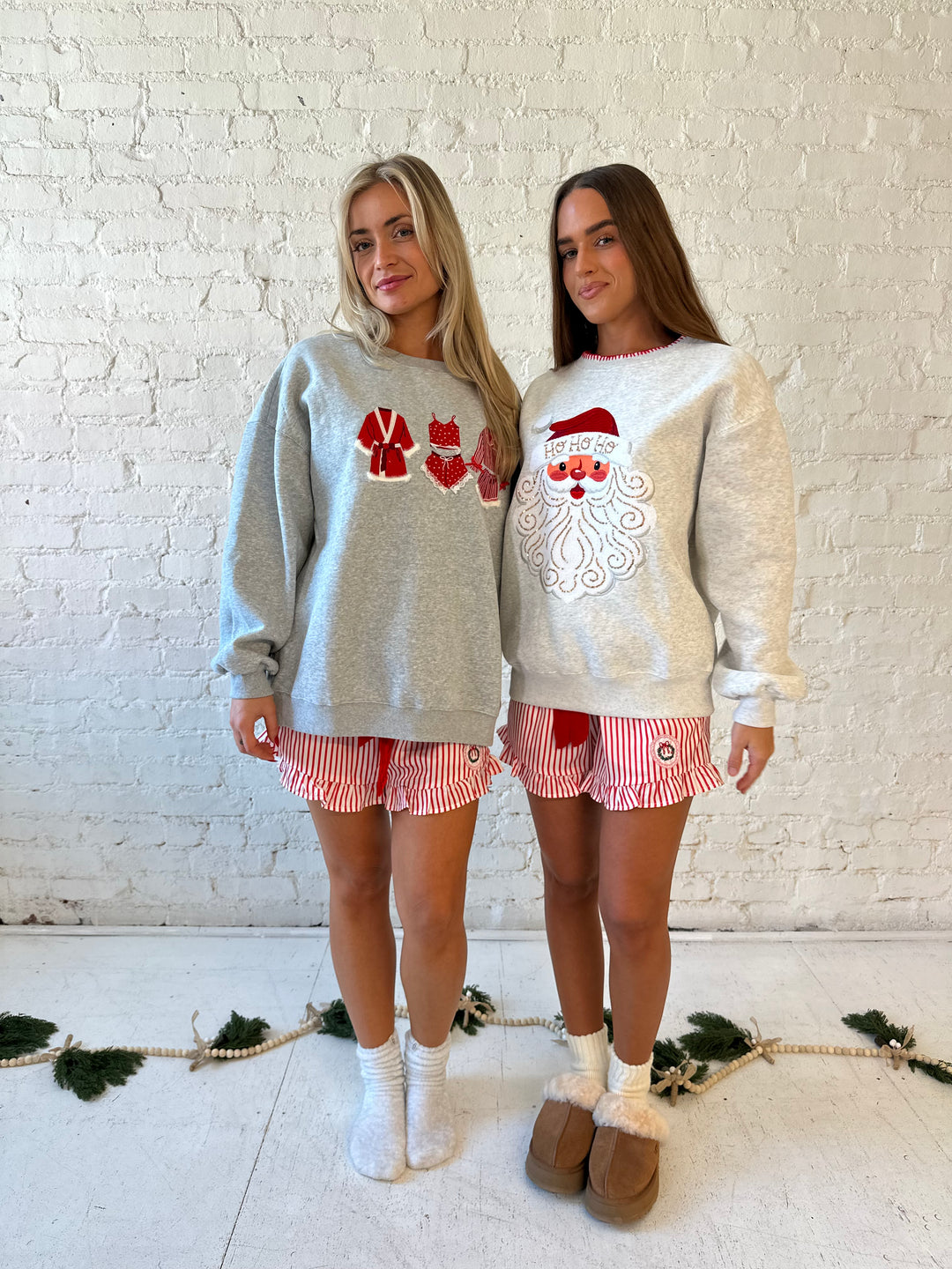 Woman wearing grey crewneck sweatshirt with red Christmas outfits embroidered on the front. 
