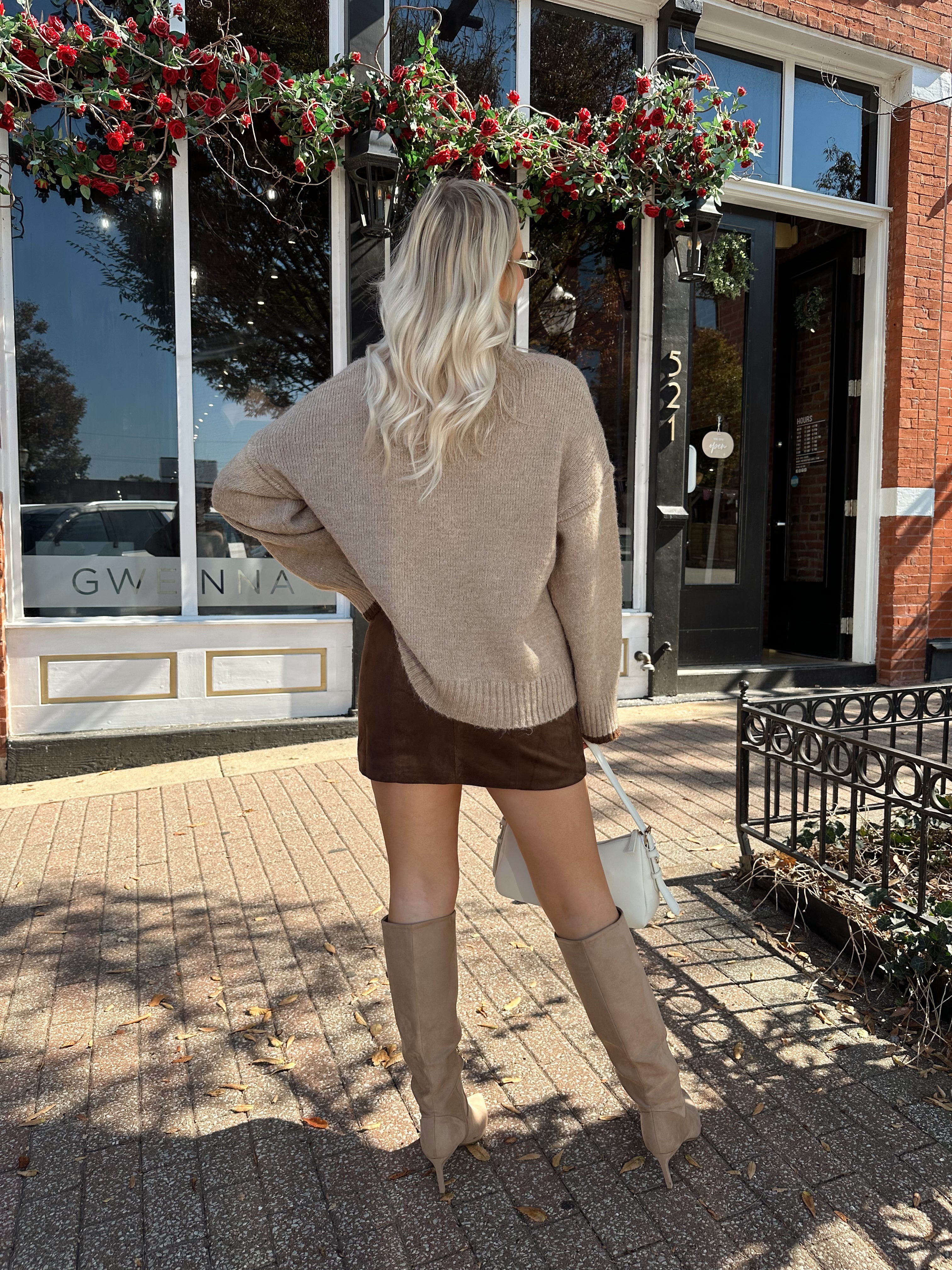 Woman wearing oversized taupe knit sweater with mocha trim detailing.