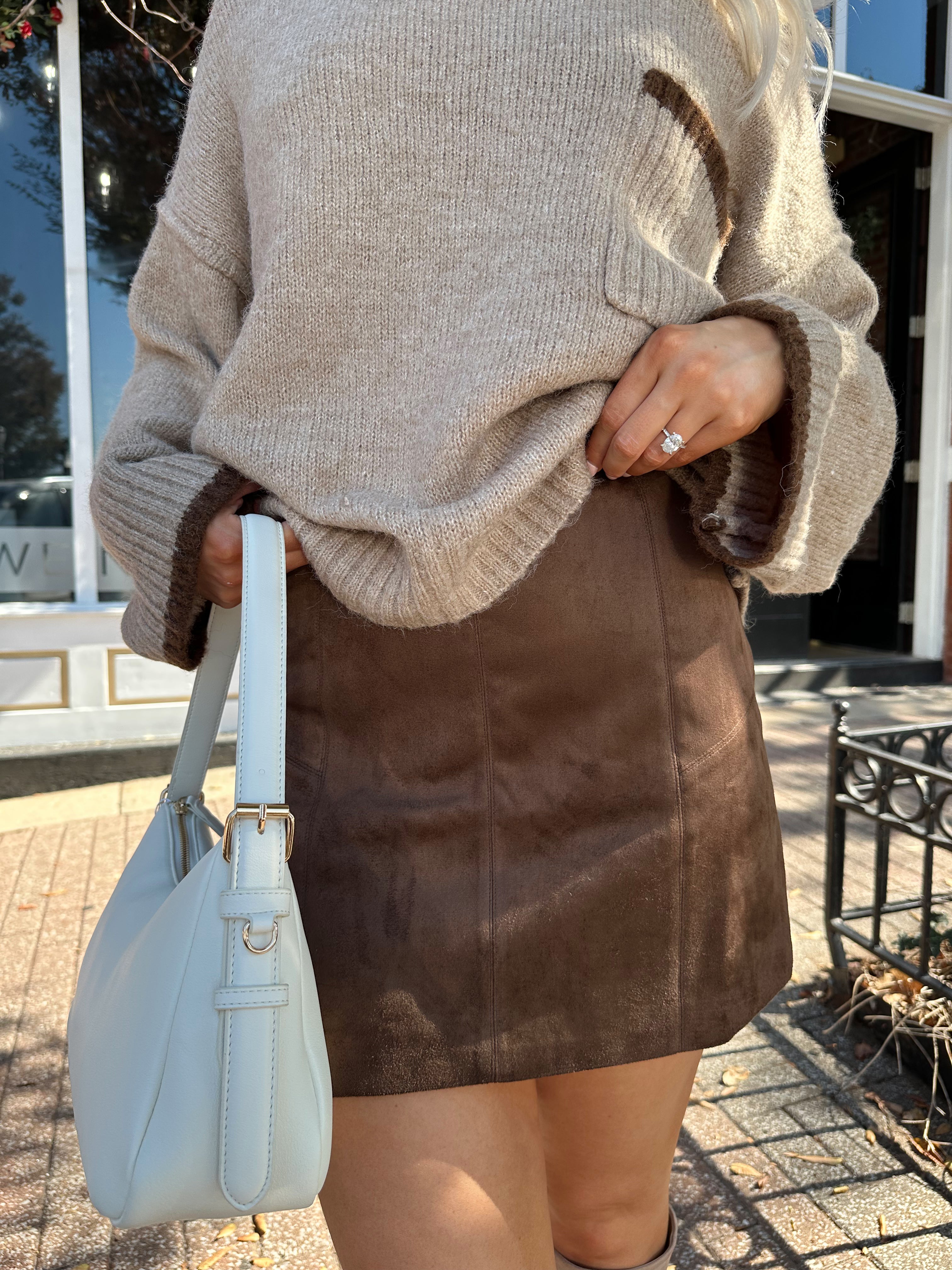Woman wearing oversized taupe knit sweater with mocha trim detailing.