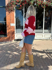 Woman wearing pink and red striped knit front the cardigan and denim skirt.