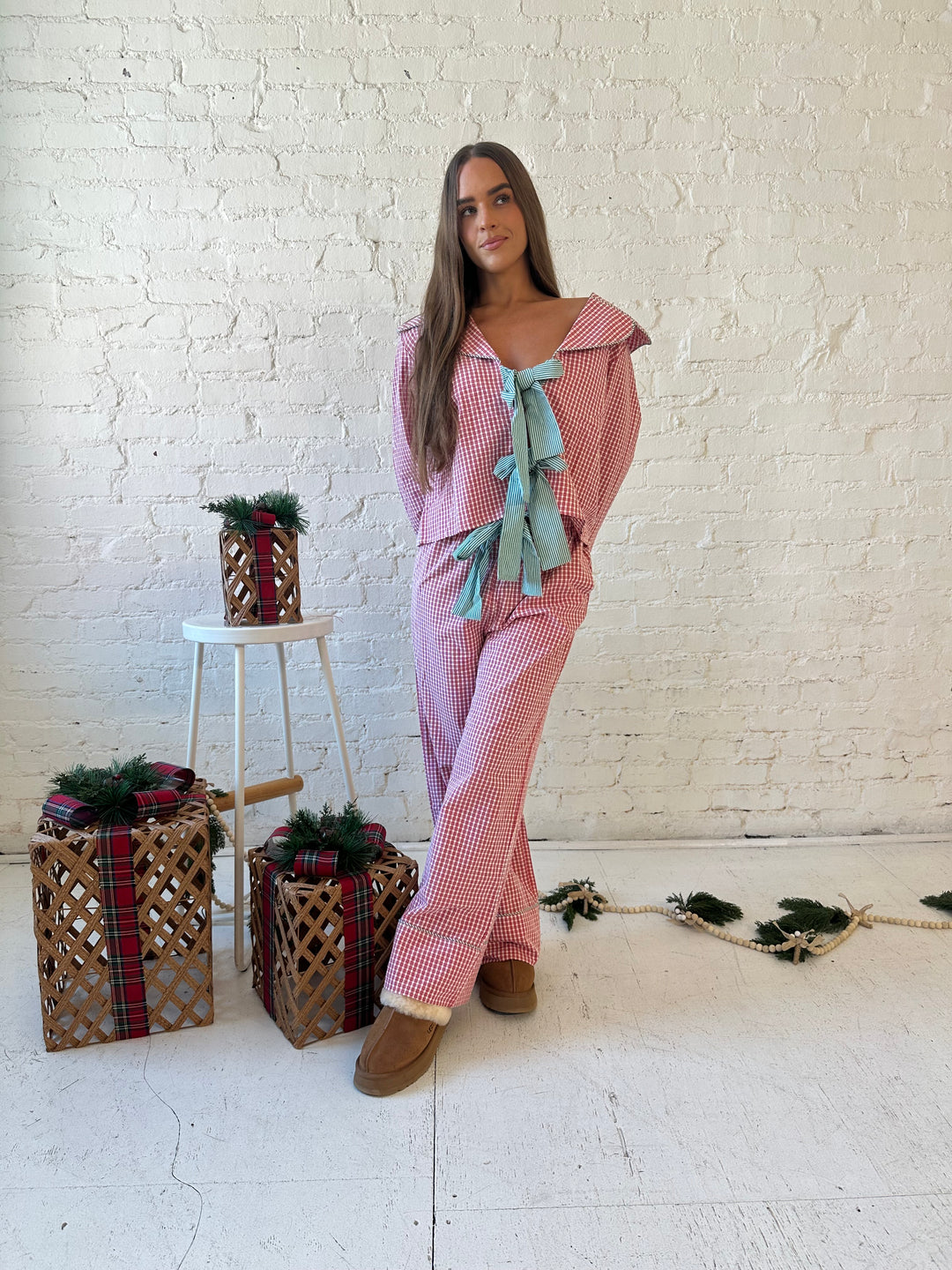 Woman wearing red gingham pajama set with front tie closure and collar detail. 