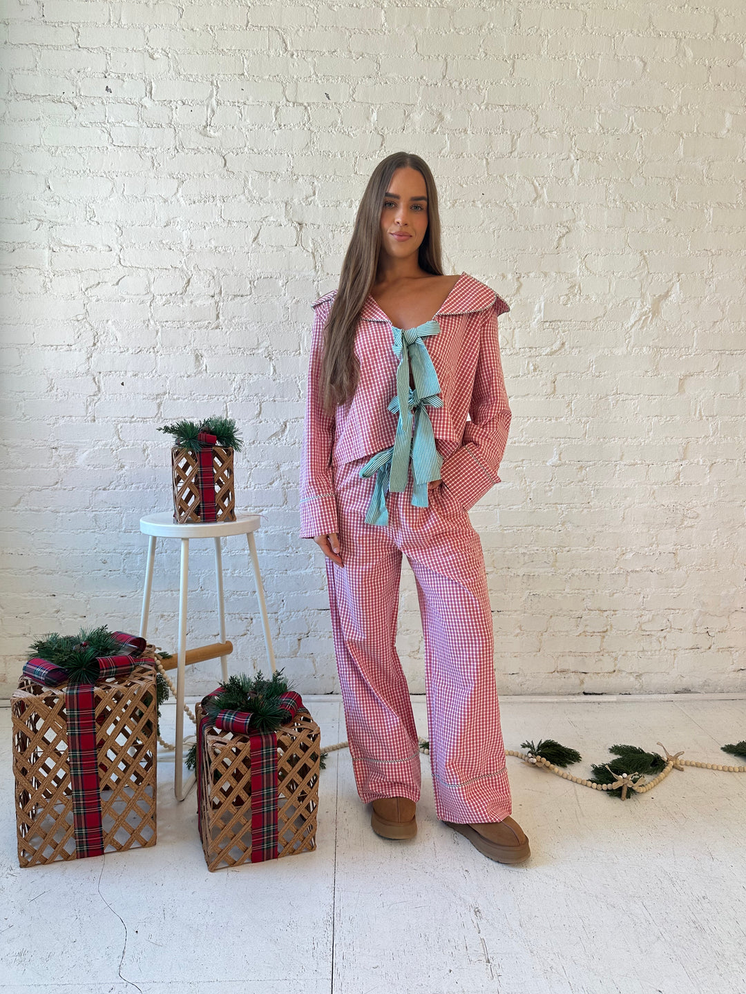 Woman wearing red gingham pajama set with front tie closure and collar detail. 