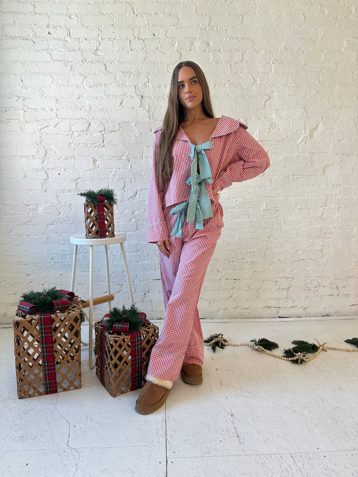 Woman wearing red gingham pajama set with front tie closure and collar detail. 