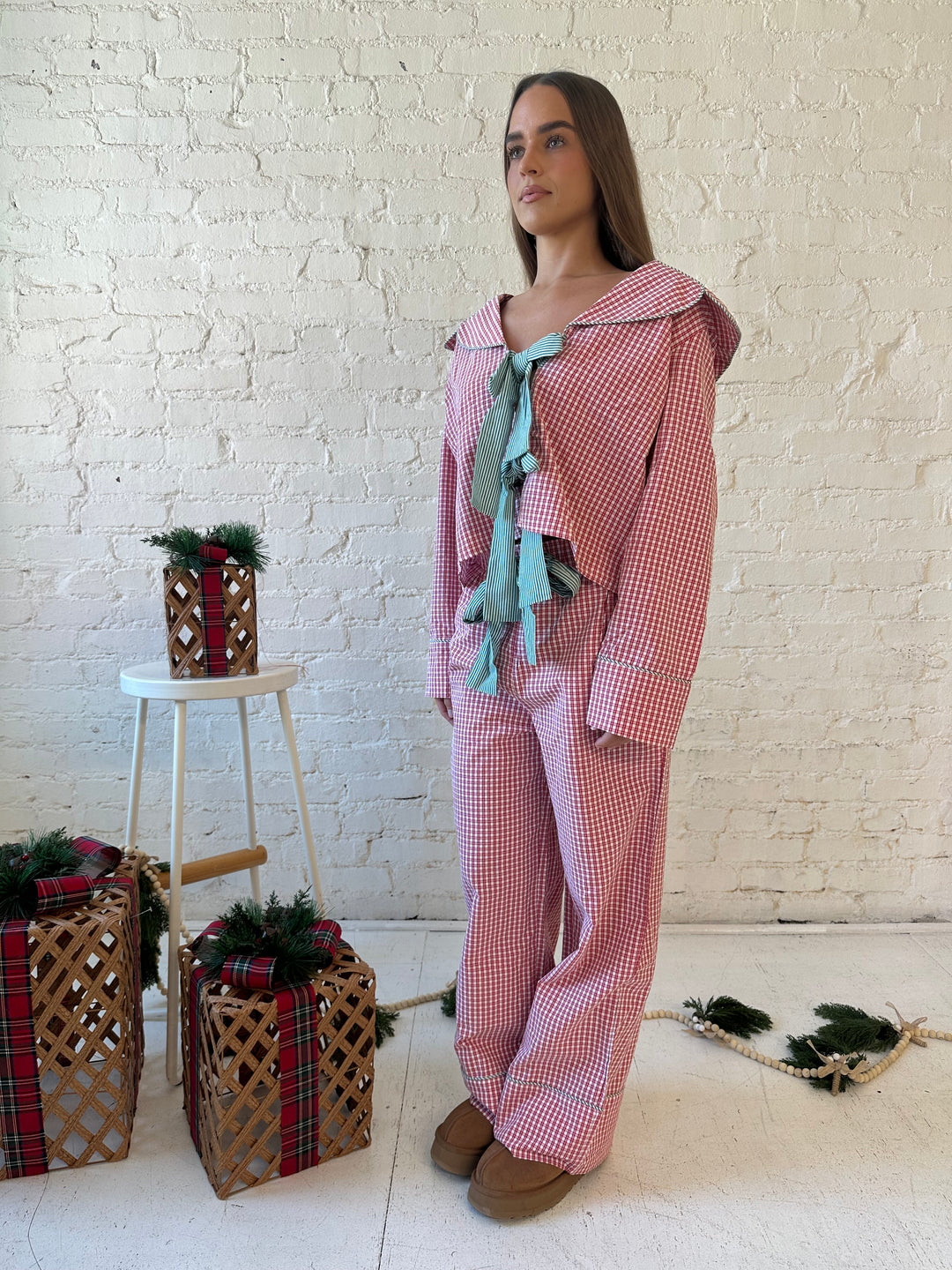 Woman wearing red gingham pajama set with front tie closure and collar detail. 