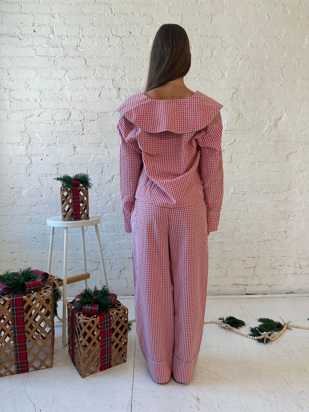 Woman wearing red gingham pajama set with front tie closure and collar detail. 