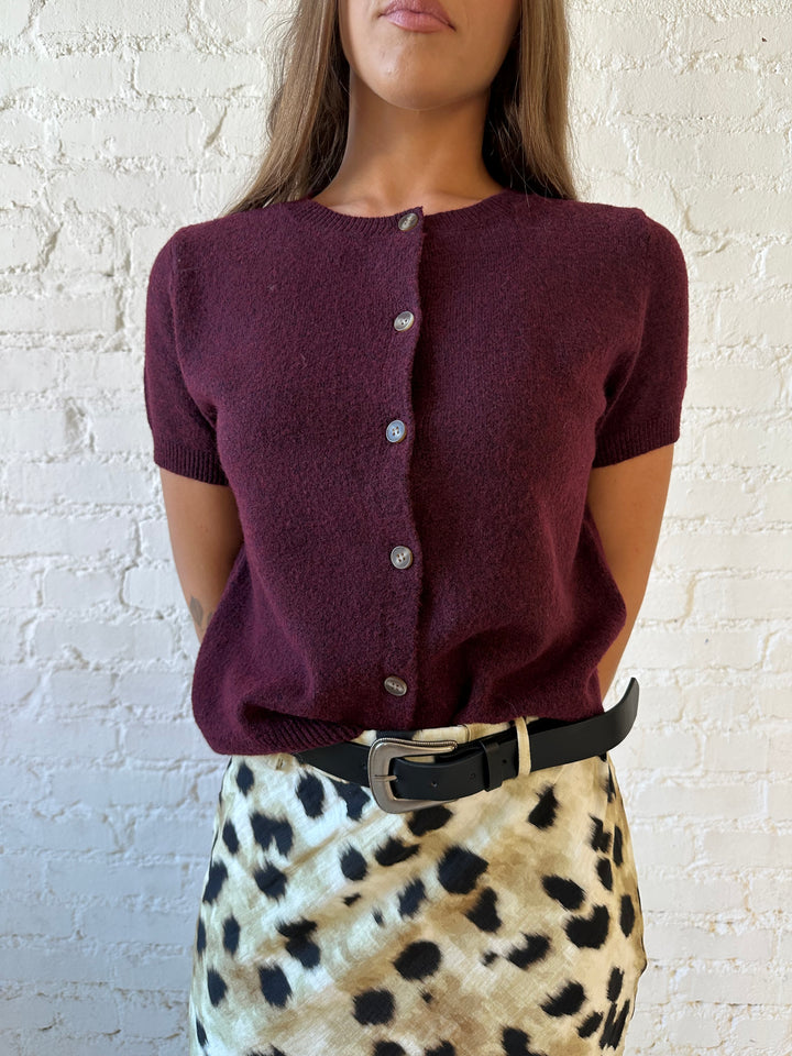 Woman wearing burgundy button down short sleeve cardigan with dark wash jeans. 