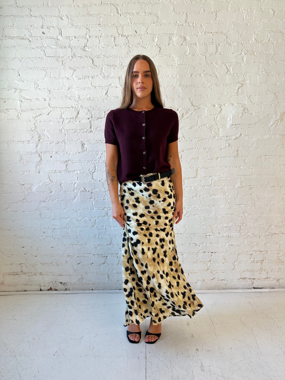 Woman wearing burgundy button down short sleeve cardigan with dark wash jeans. 