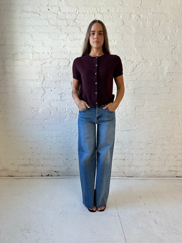 Woman wearing burgundy button down short sleeve cardigan with dark wash jeans. 