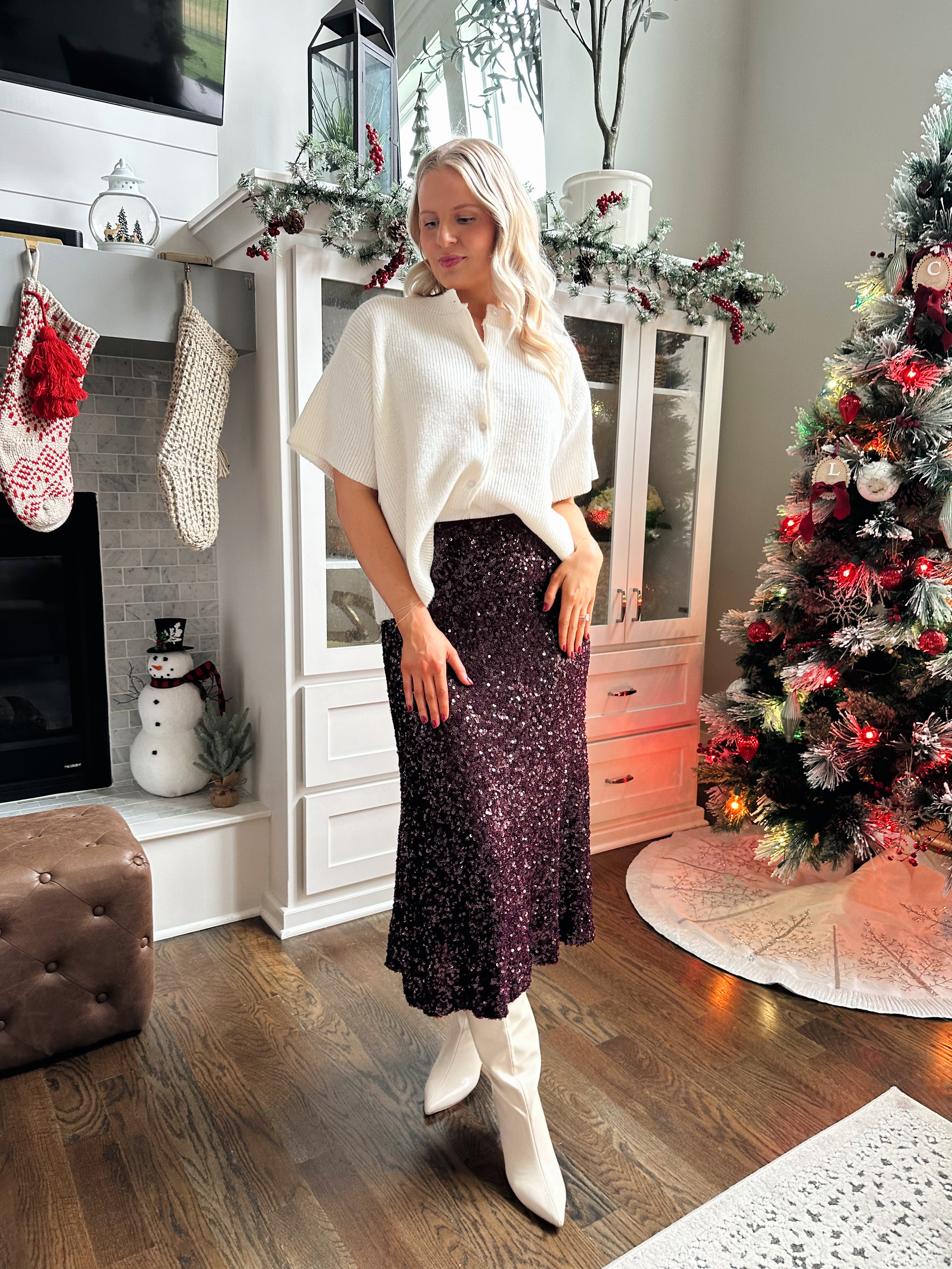 Woman wearing burgundy sequin midi skirt with knit button up sweater top.