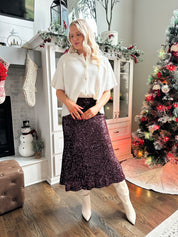 Woman wearing burgundy sequin midi skirt with knit button up sweater top.