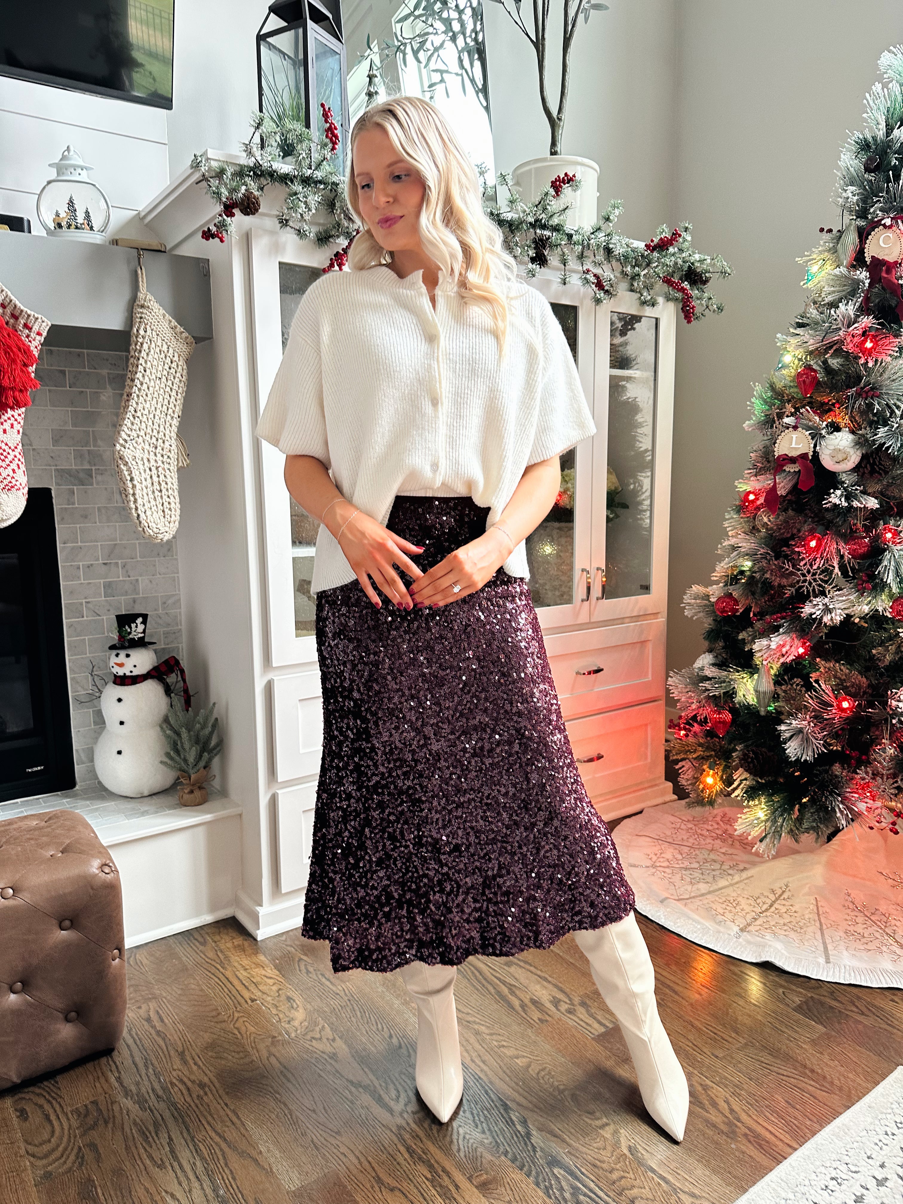 Woman wearing burgundy sequin midi skirt with knit button up sweater top.