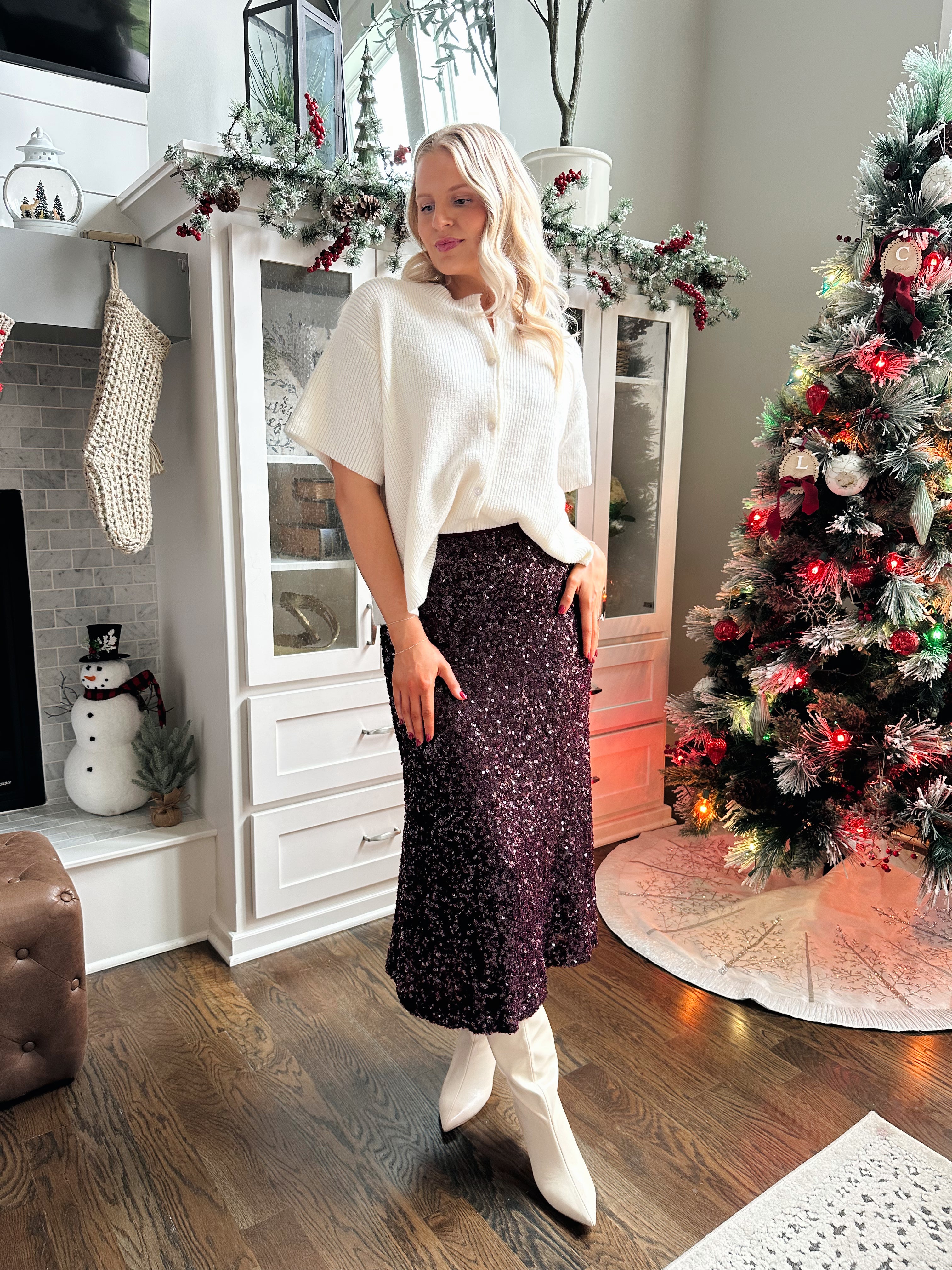 Woman wearing burgundy sequin midi skirt with knit button up sweater top.