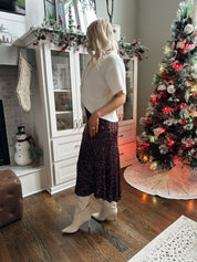 Woman wearing burgundy sequin midi skirt with knit button up sweater top.