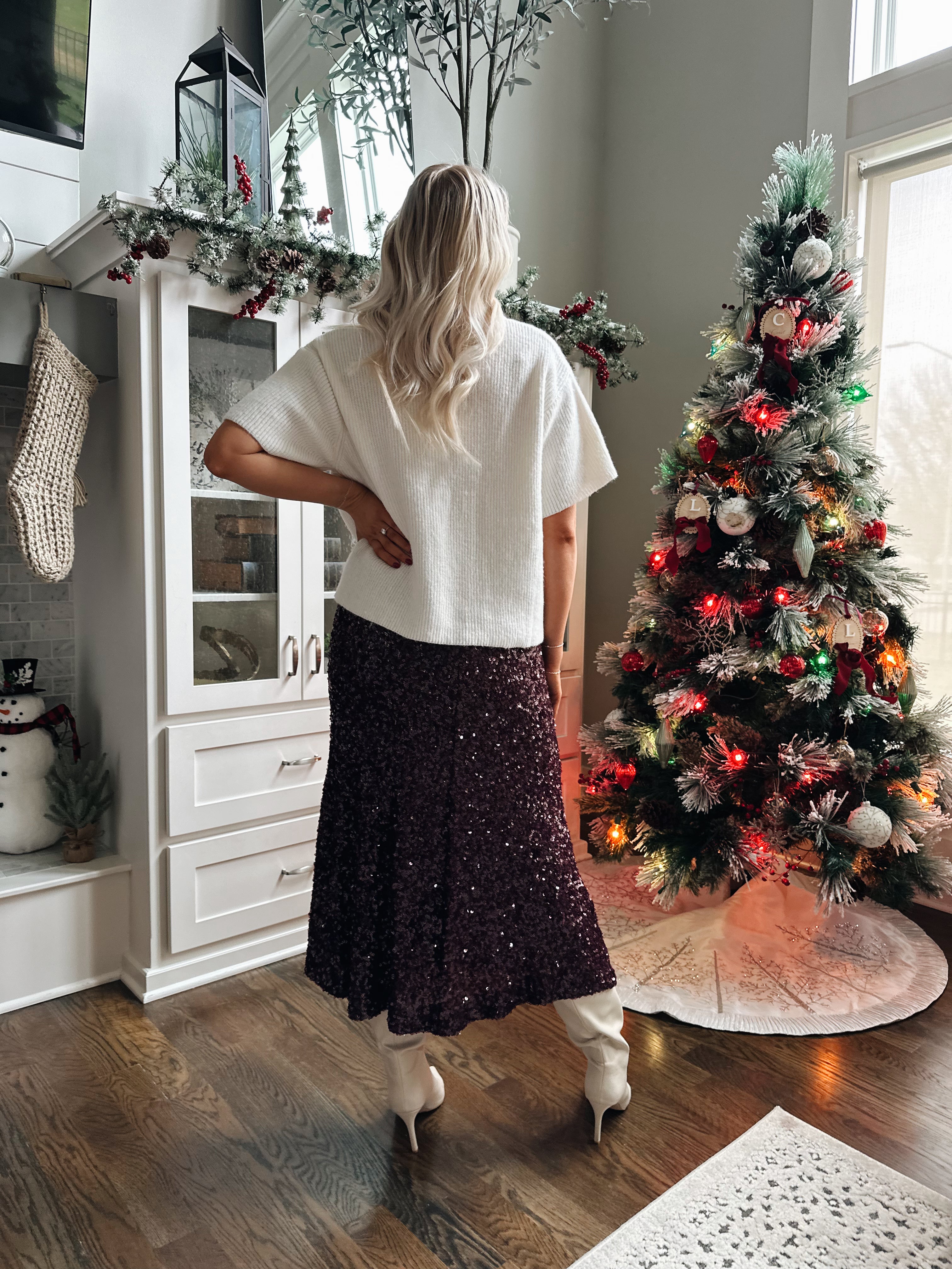 Woman wearing burgundy sequin midi skirt with knit button up sweater top.