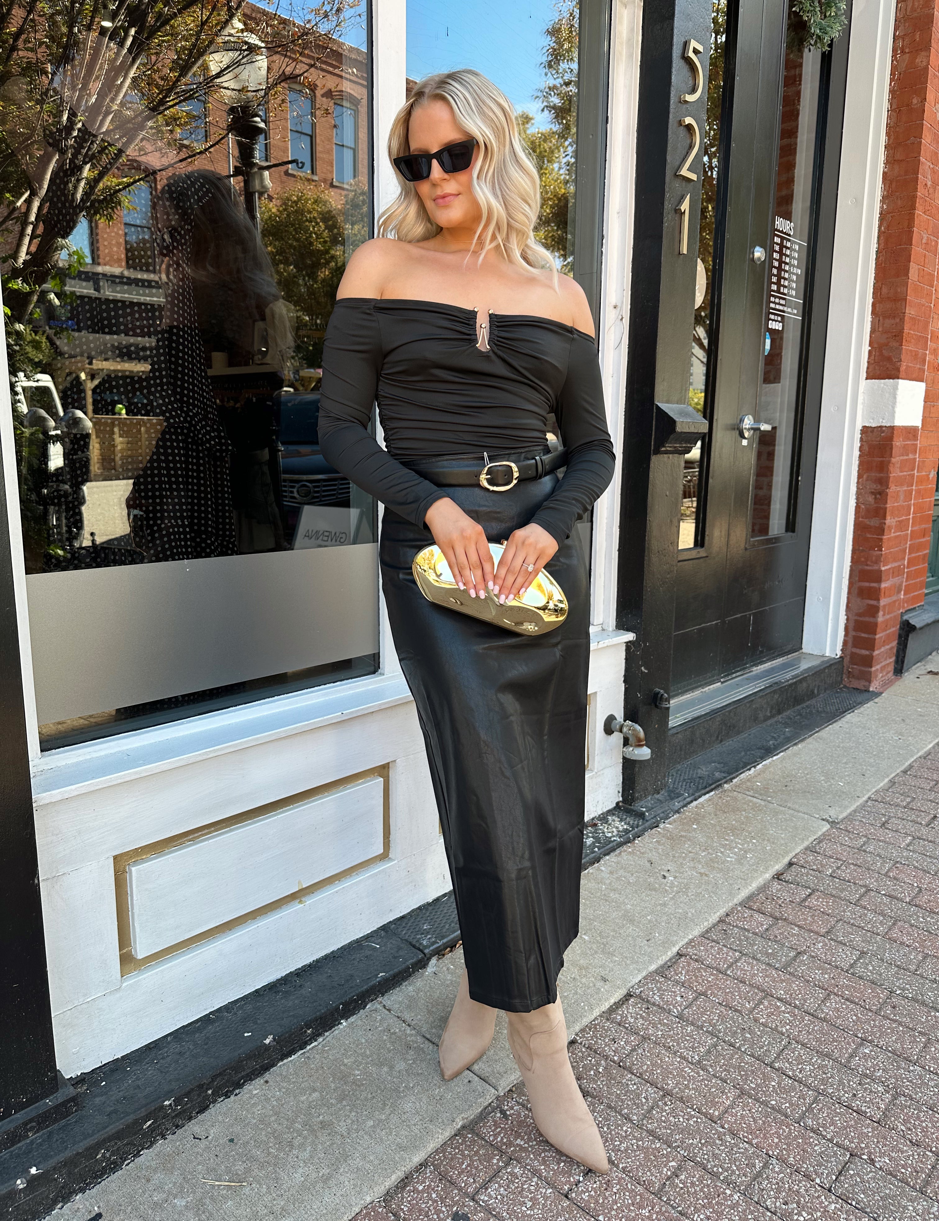 Woman wearing black leather midi skirt with slit up the back.