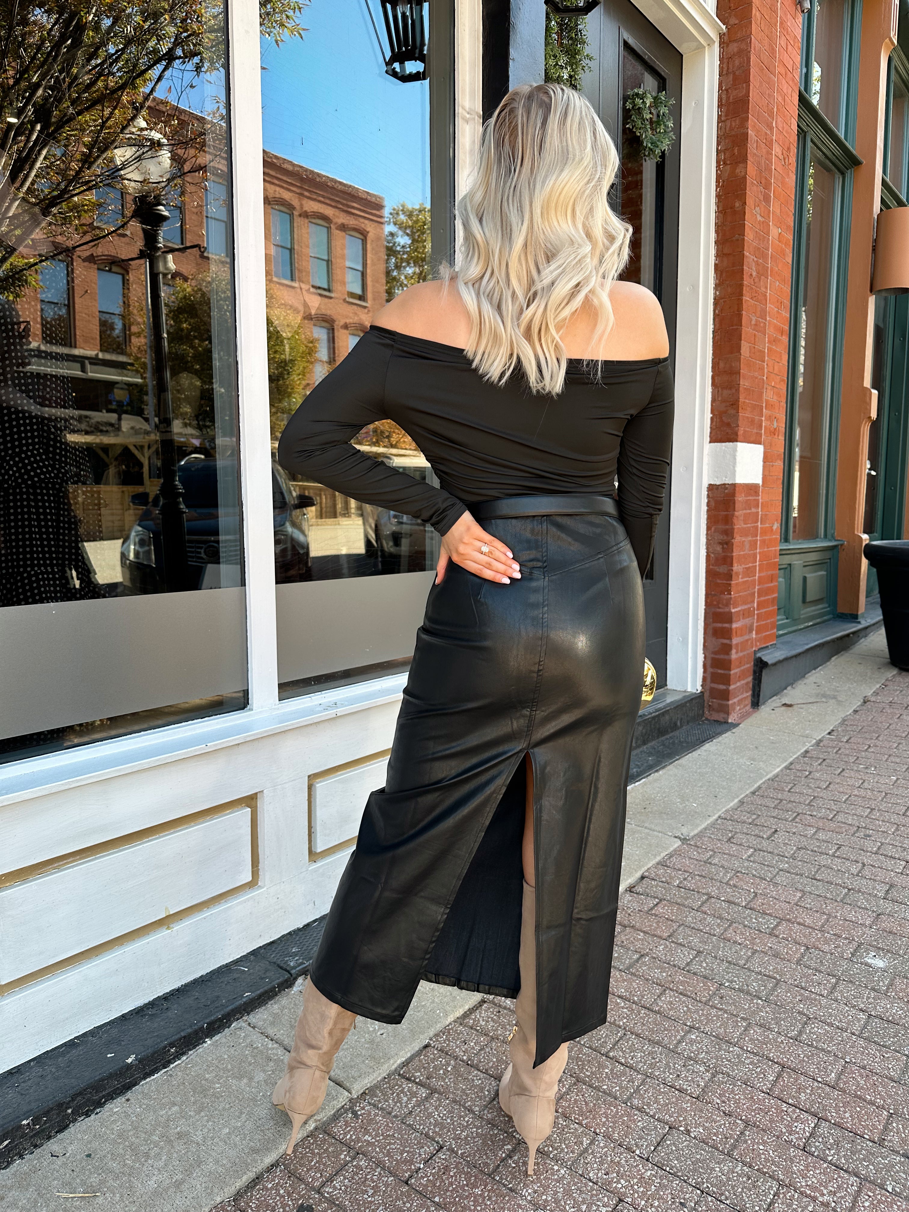 Woman wearing black leather midi skirt with slit up the back.