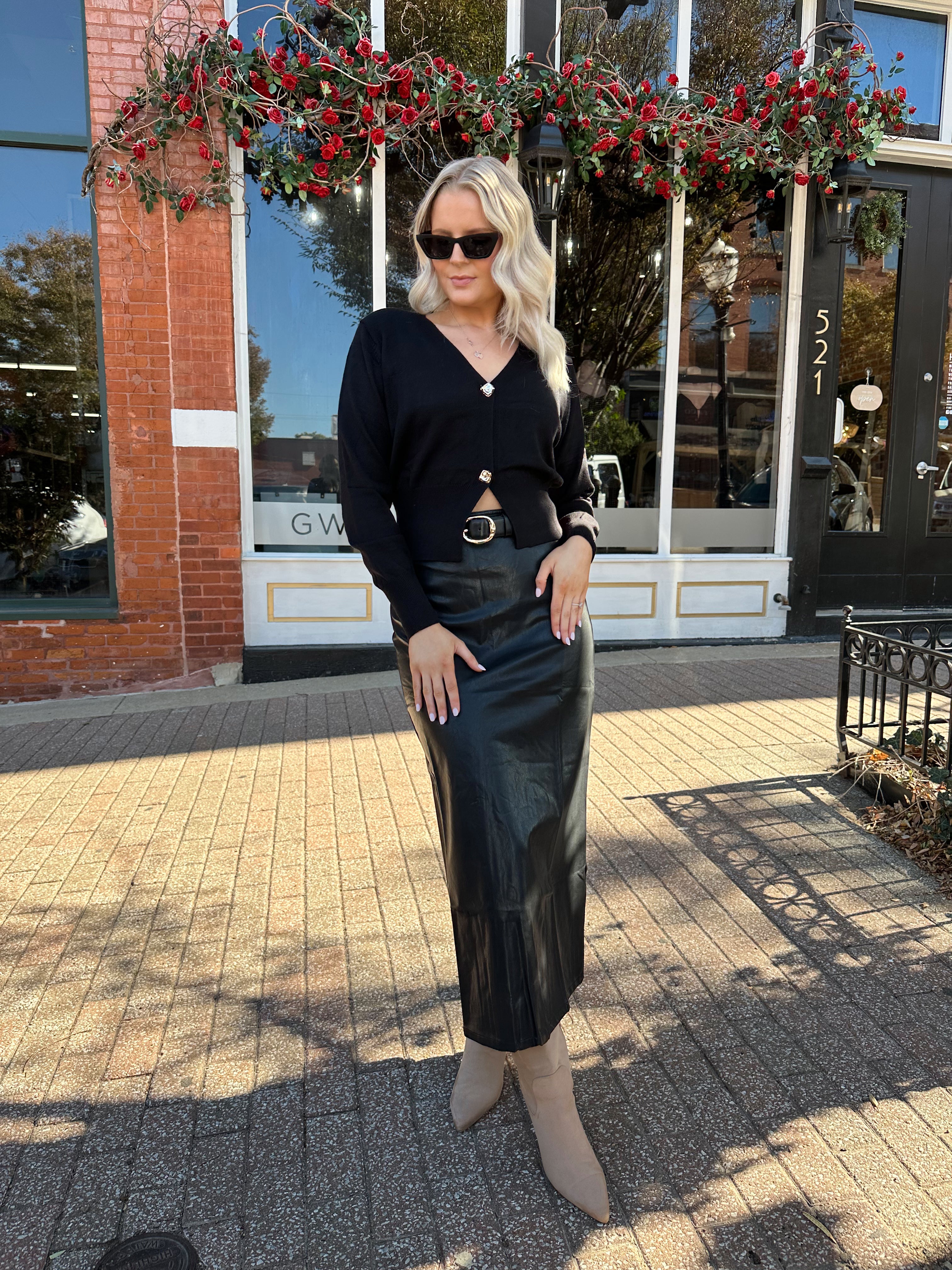 Woman wearing black leather midi skirt with slit up the back.