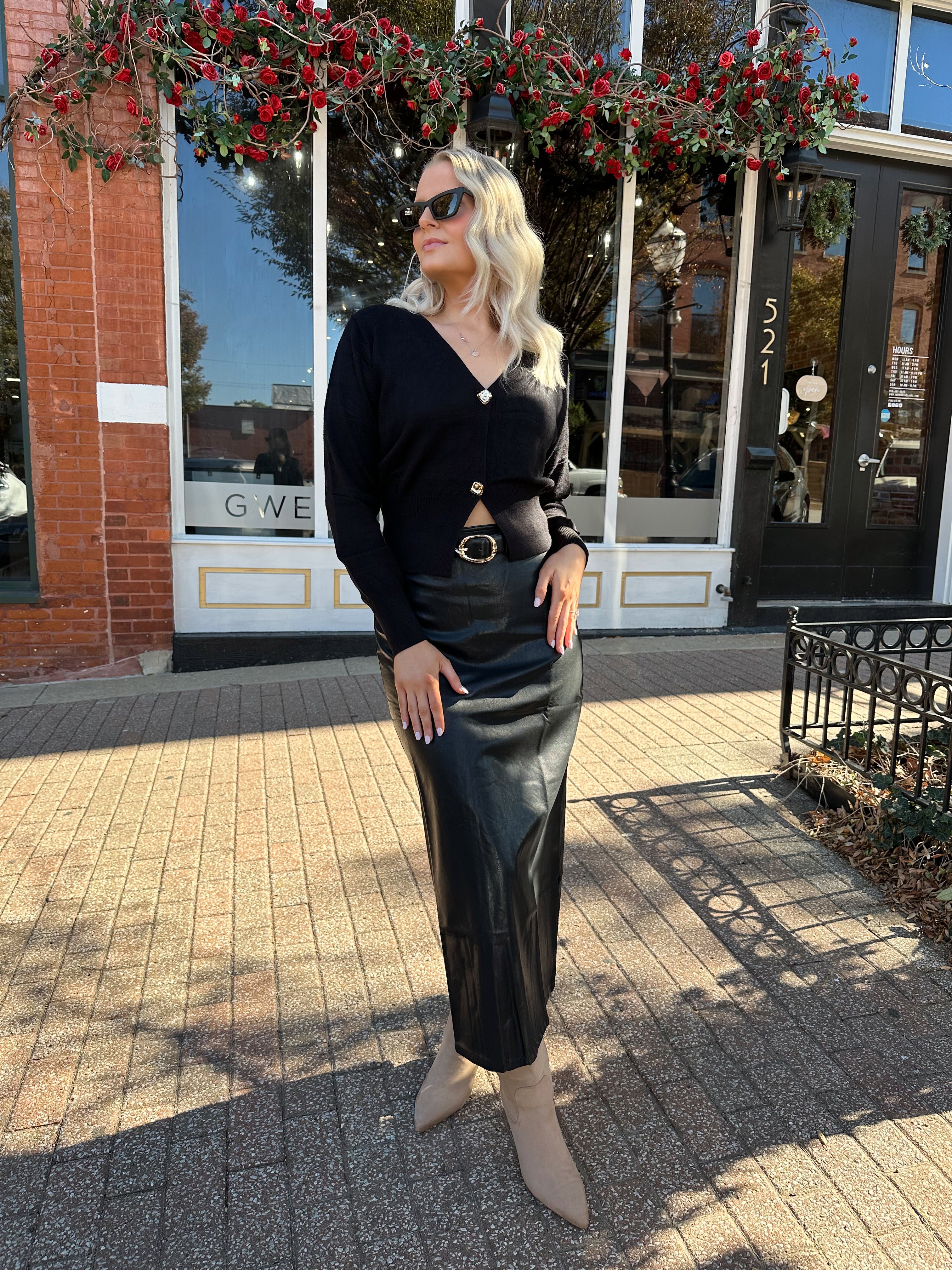 Woman wearing black leather midi skirt with slit up the back.