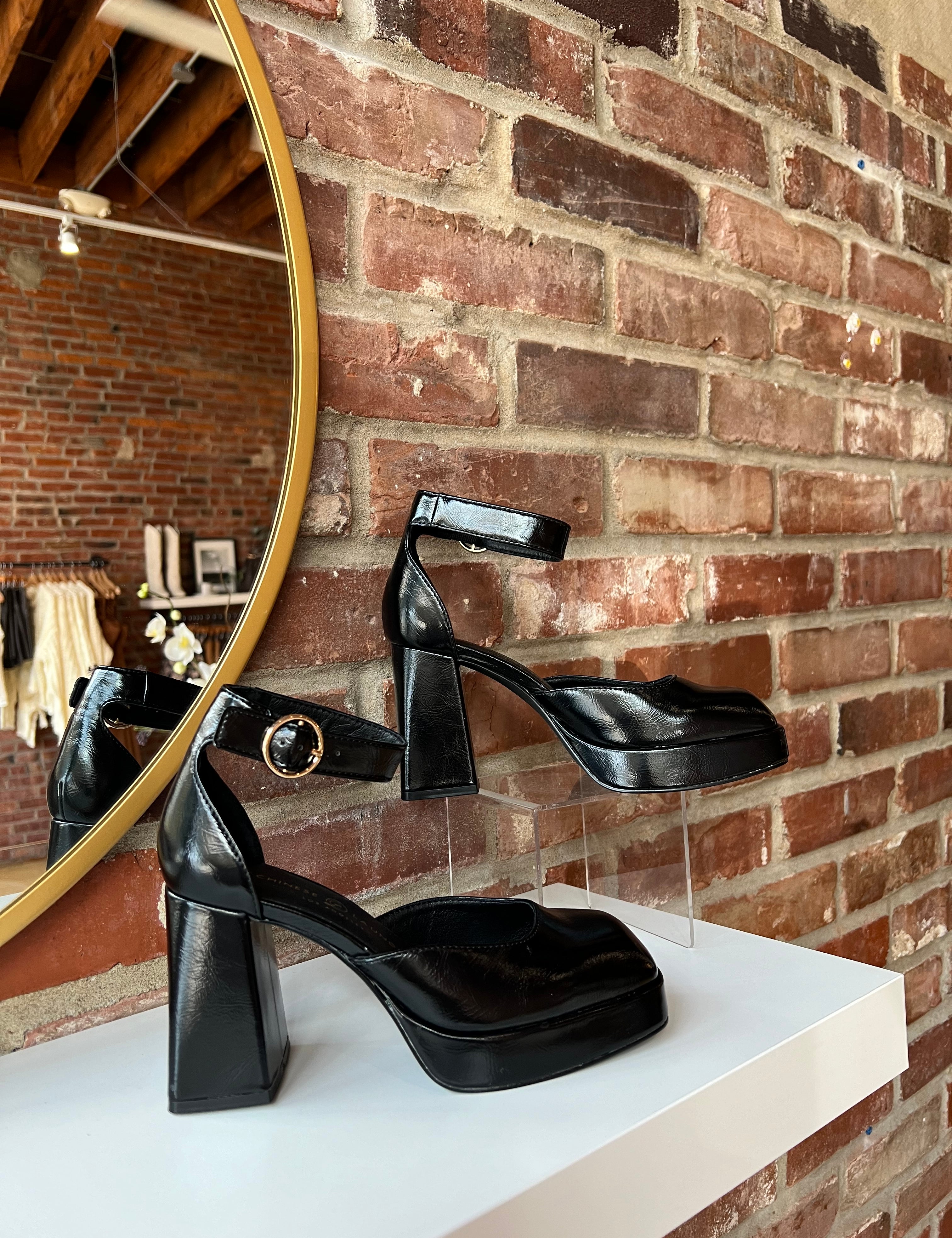Black patent platform heel with closed toed front and ankle strap.