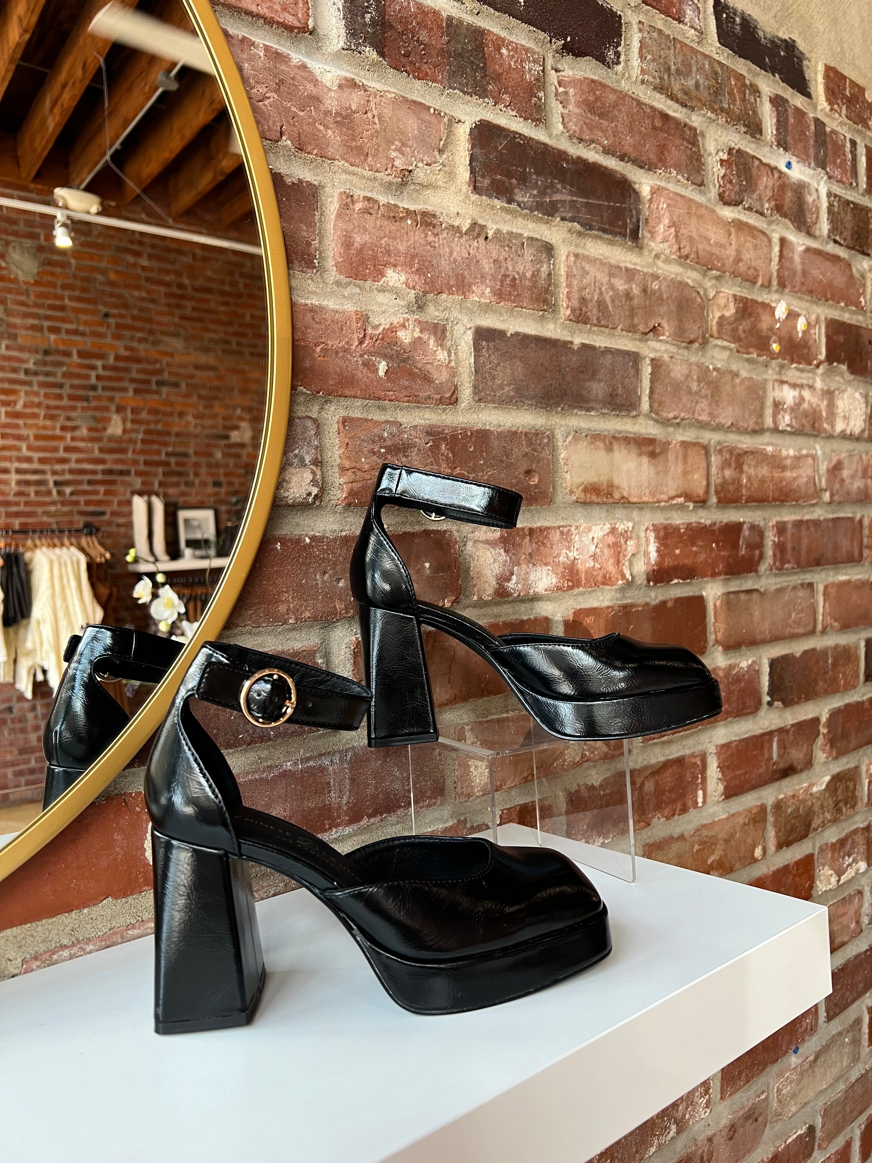 Black patent platform heel with closed toed front and ankle strap.