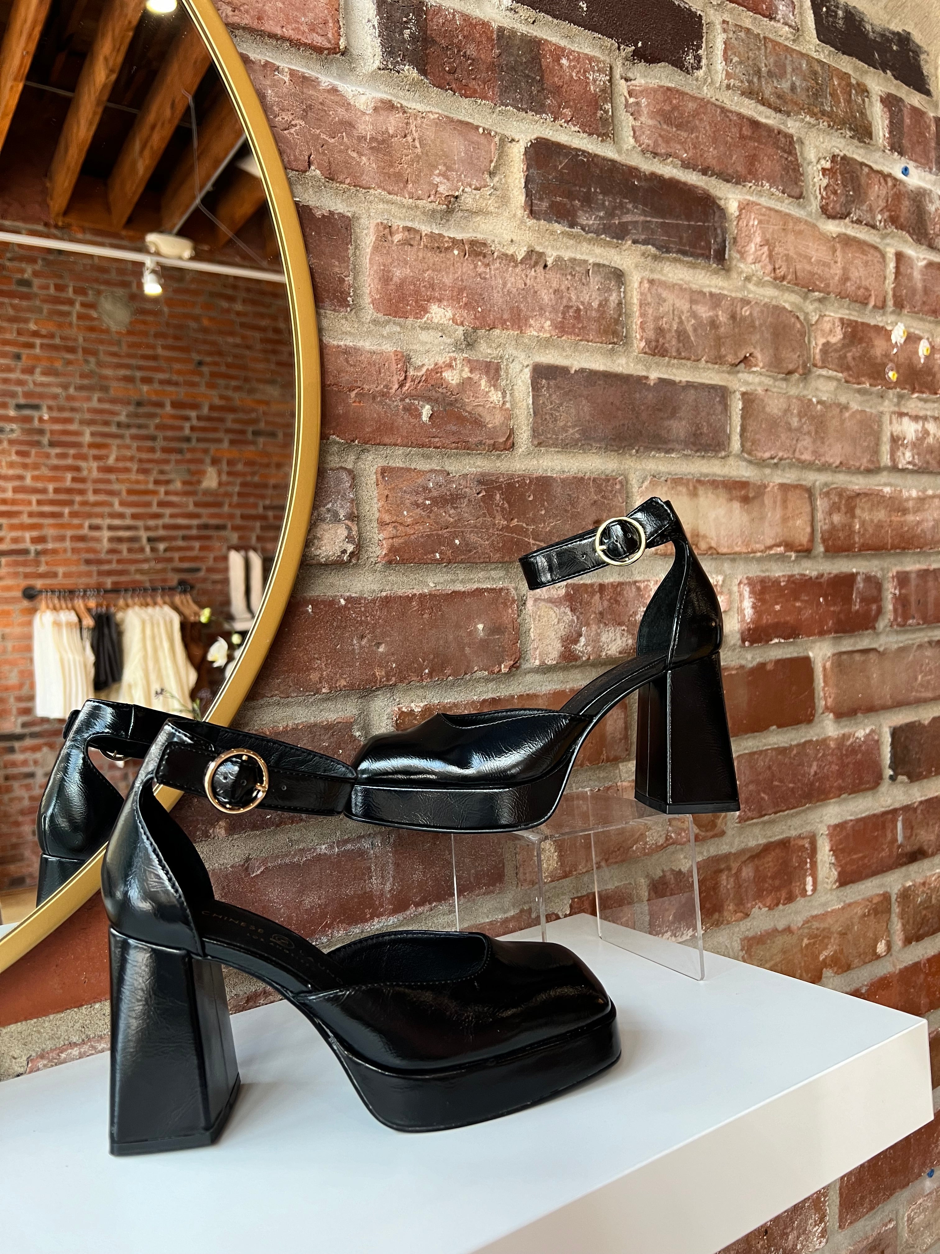 Black patent platform heel with closed toed front and ankle strap.