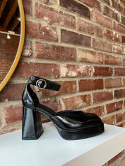 Black patent platform heel with closed toed front and ankle strap.