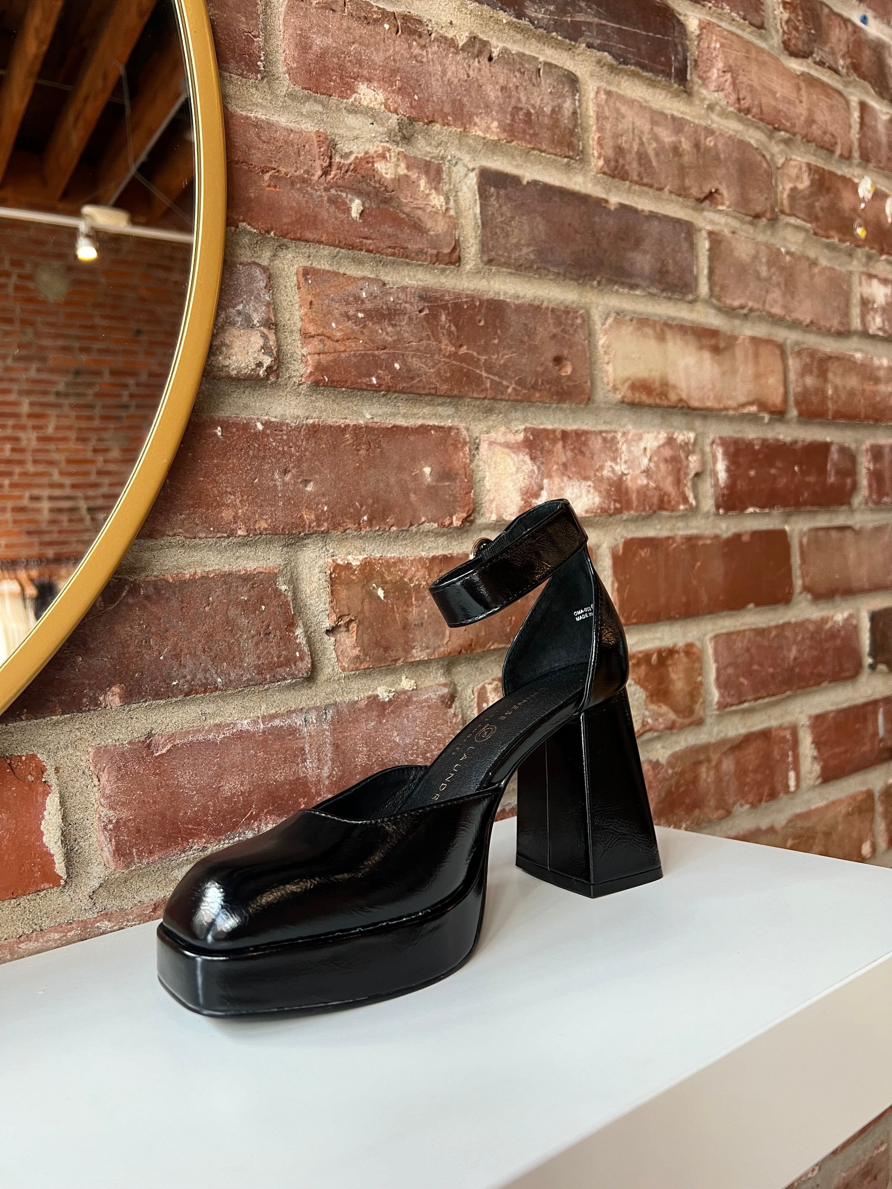Black patent platform heel with closed toed front and ankle strap.