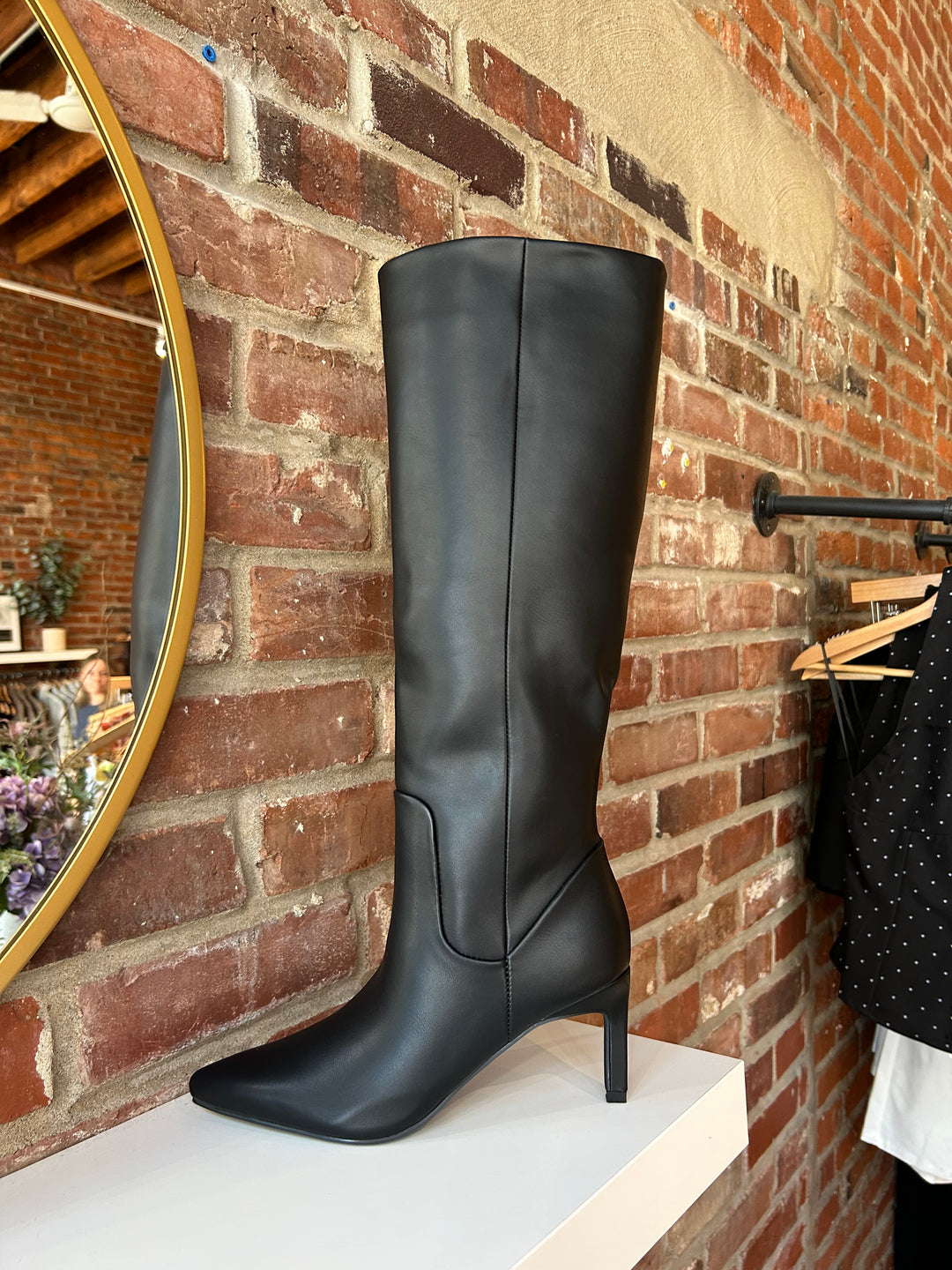 Tall black leather knee boot with inner zipper closure. 