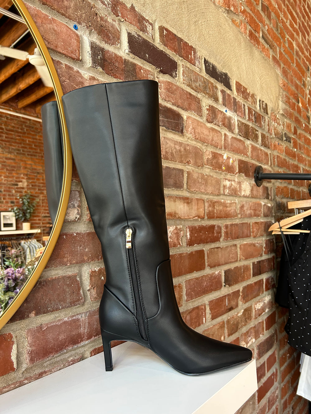 Tall black leather knee boot with inner zipper closure. 