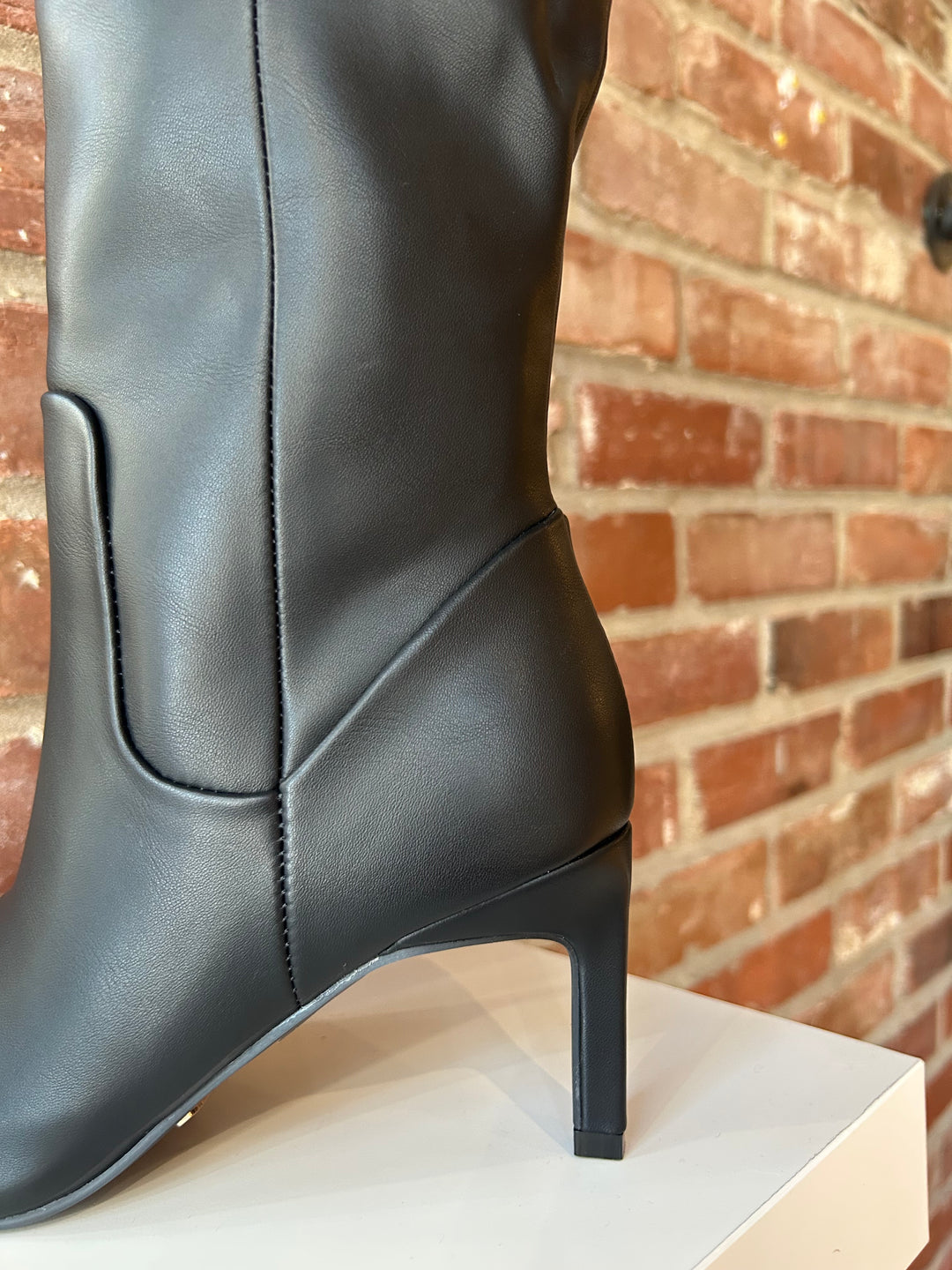 Tall black leather knee boot with inner zipper closure. 