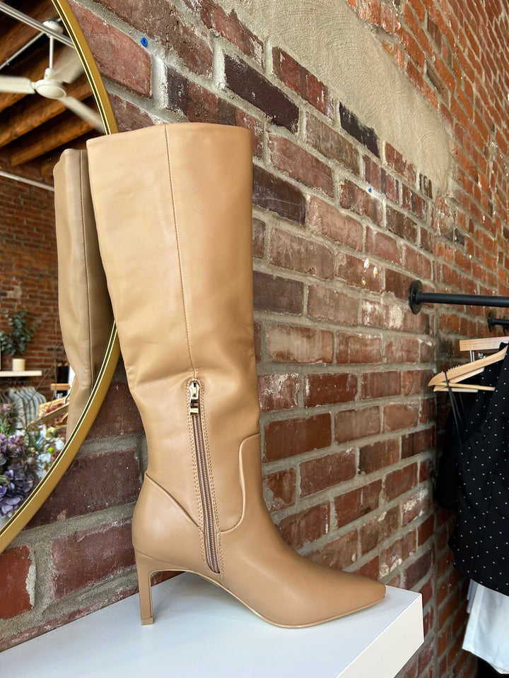Woman wearing camel colored leather knee boot with inner zipper closure. 