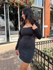 Woman wearing black long sleeve square neck mini dress with suede knee boot.