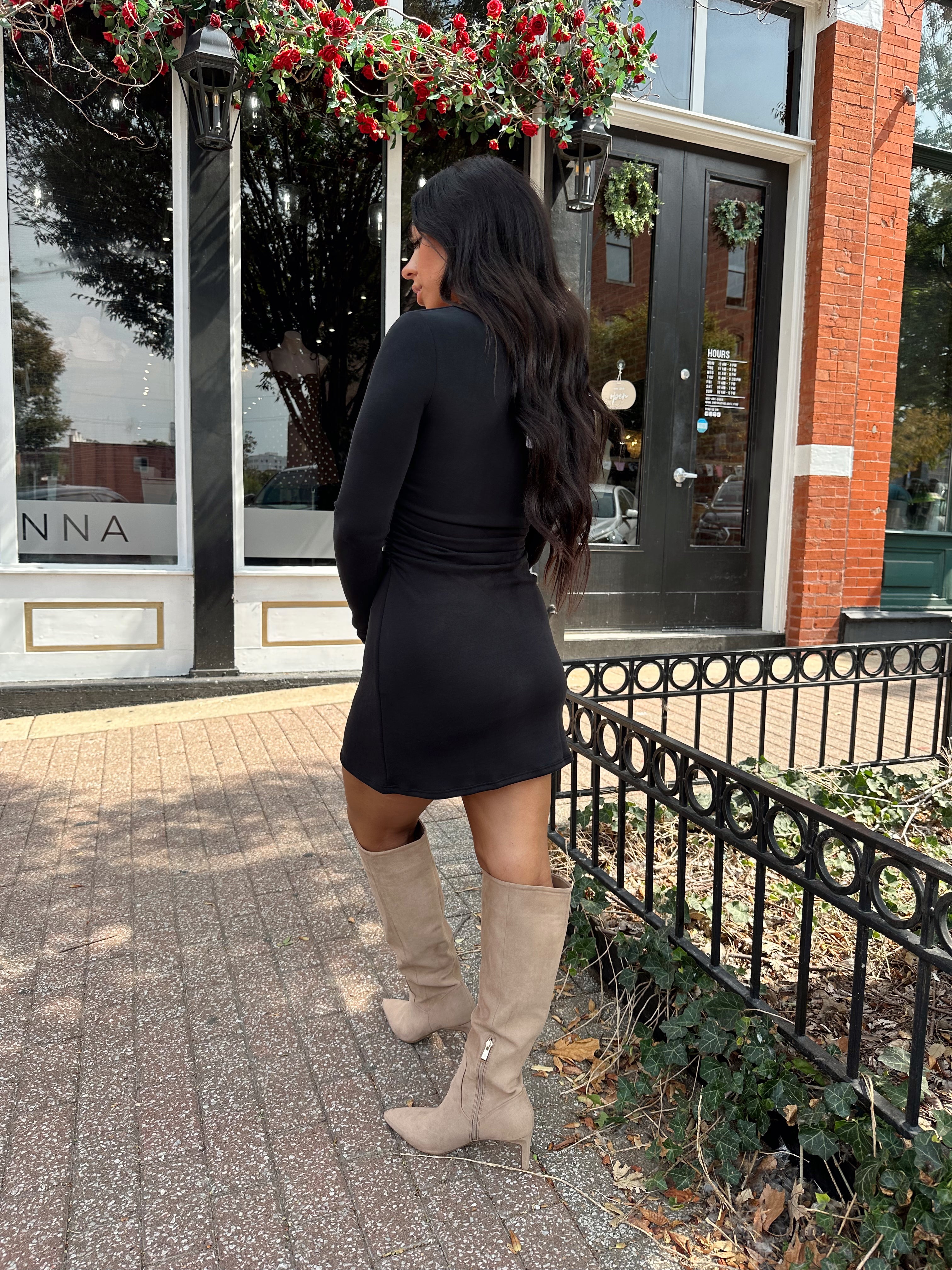 Woman wearing black long sleeve square neck mini dress with suede knee boot.