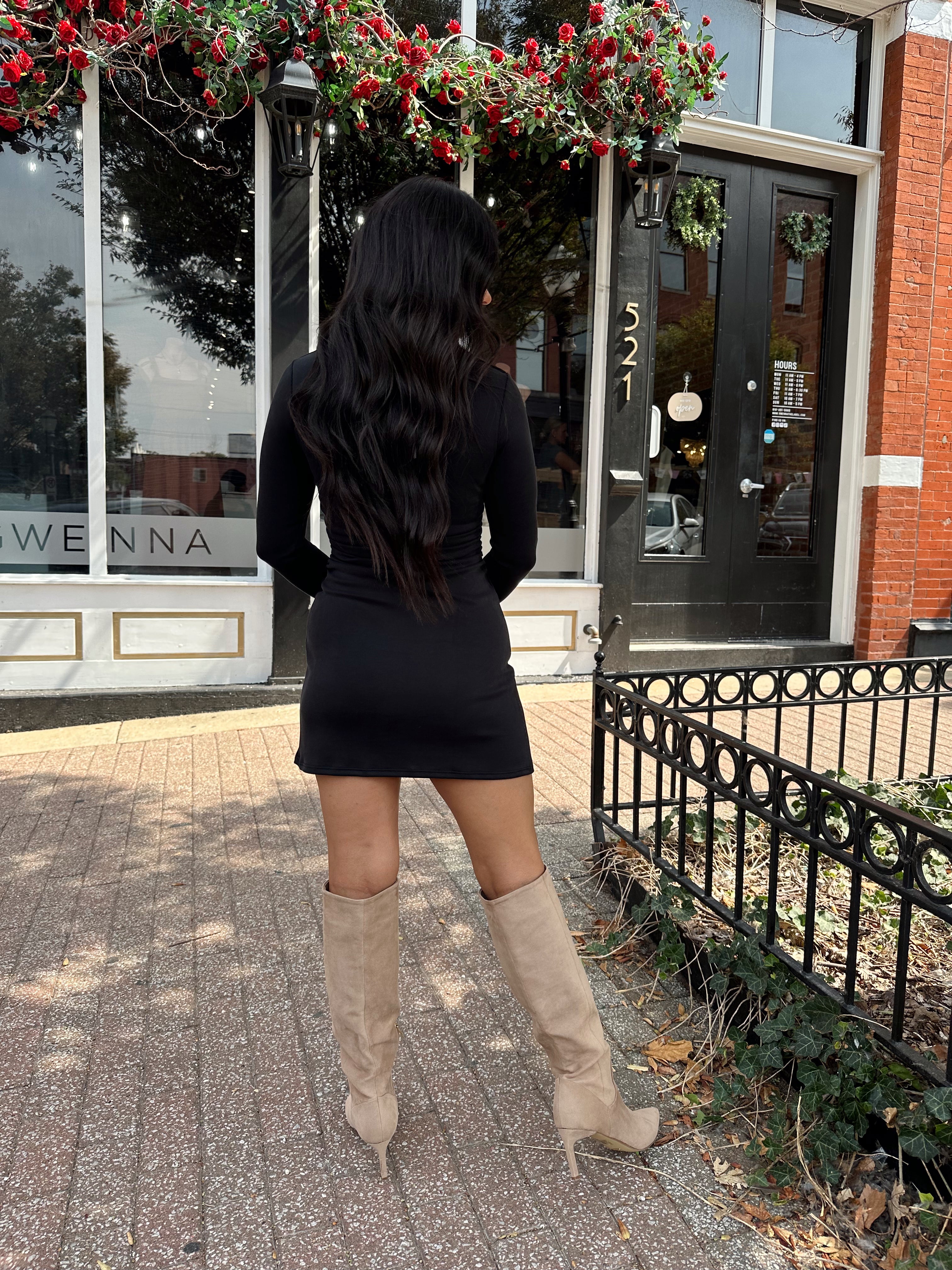 Woman wearing black long sleeve square neck mini dress with suede knee boot.