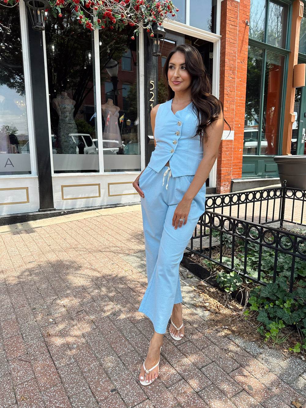 Woman wearing light blue two piece set with vest top, and high waisted pant with draw string waist.