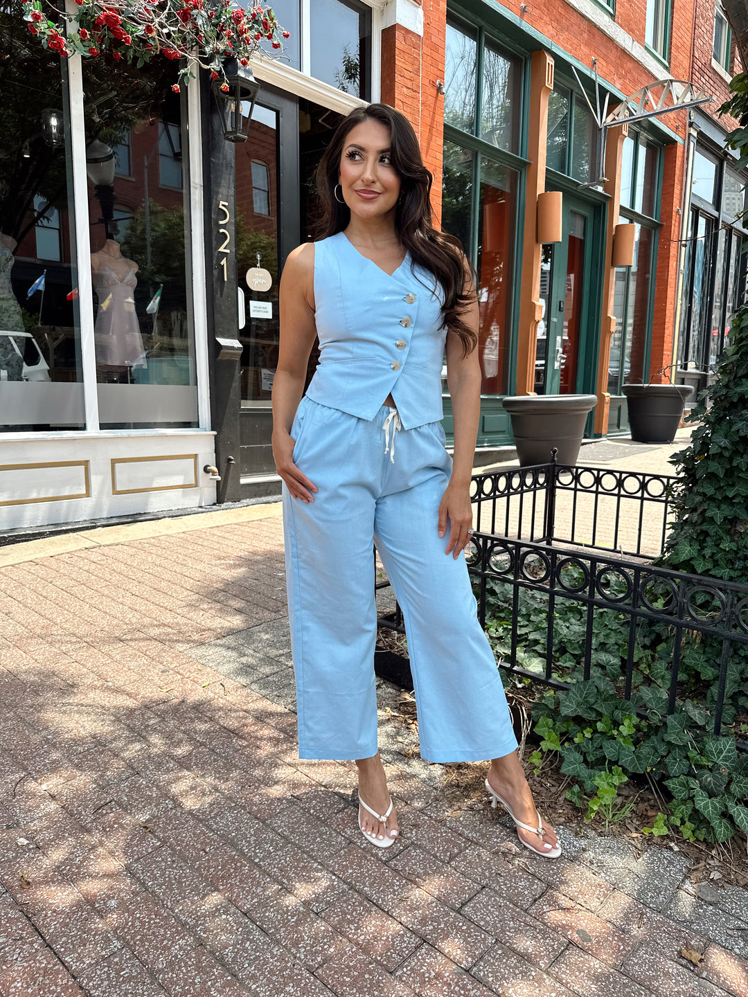 Woman wearing light blue two piece set with vest top, and high waisted pant with draw string waist.
