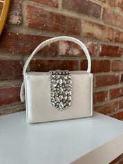 Liliana Purse with a satin finish, rhinestone embellishments, and a structured top handle for a chic and elegant look.