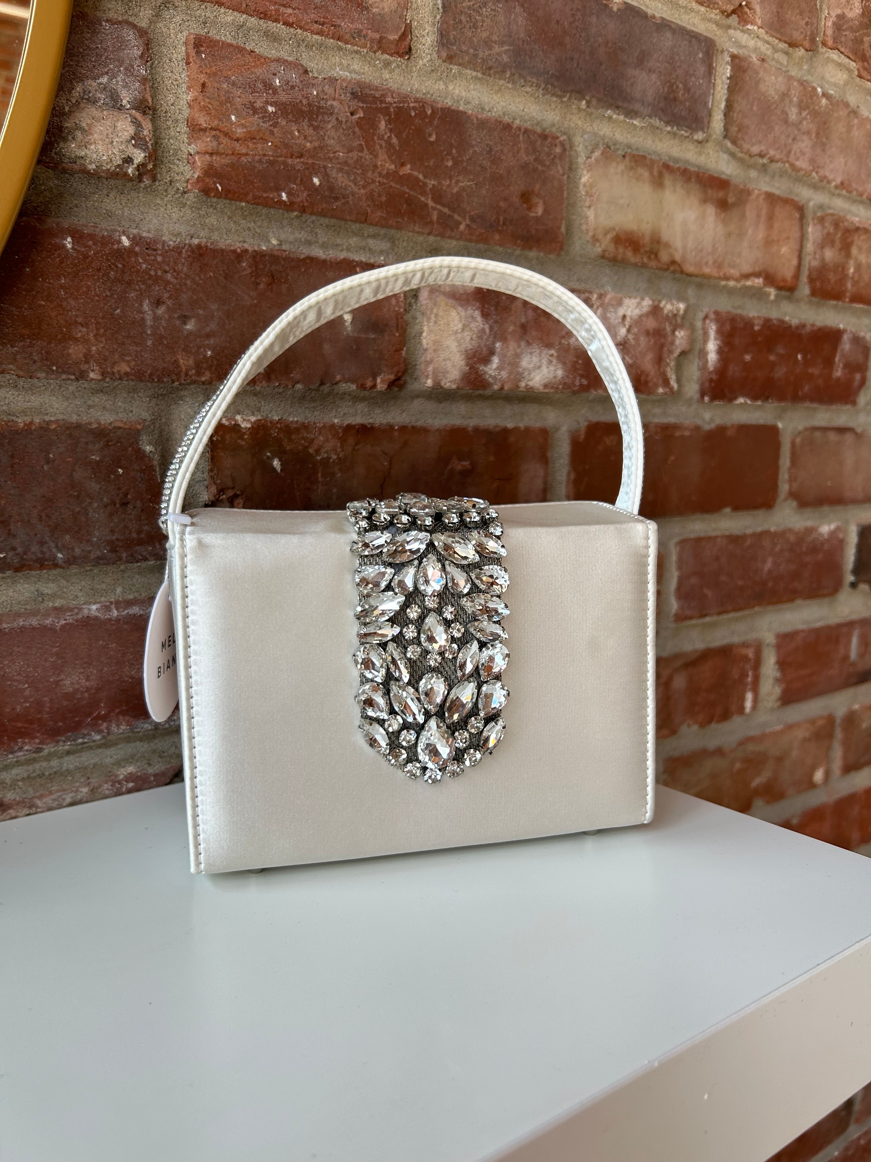 Liliana Purse with a satin finish, rhinestone embellishments, and a structured top handle for a chic and elegant look.