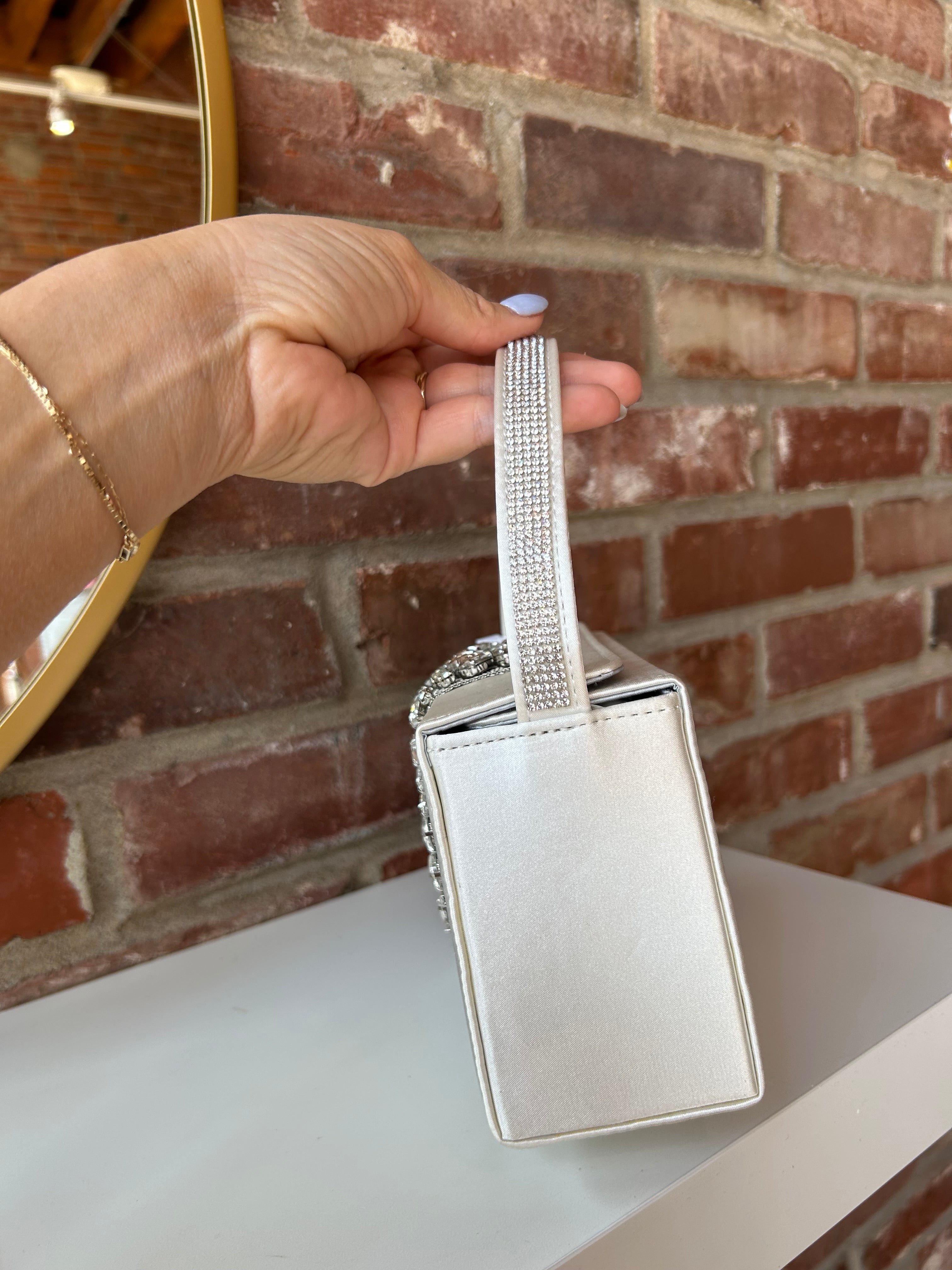 Liliana Purse with a satin finish, rhinestone embellishments, and a structured top handle for a chic and elegant look.