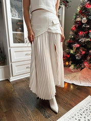 Woman wearing ivory asymmetrical maxi skirt with plated bottom.