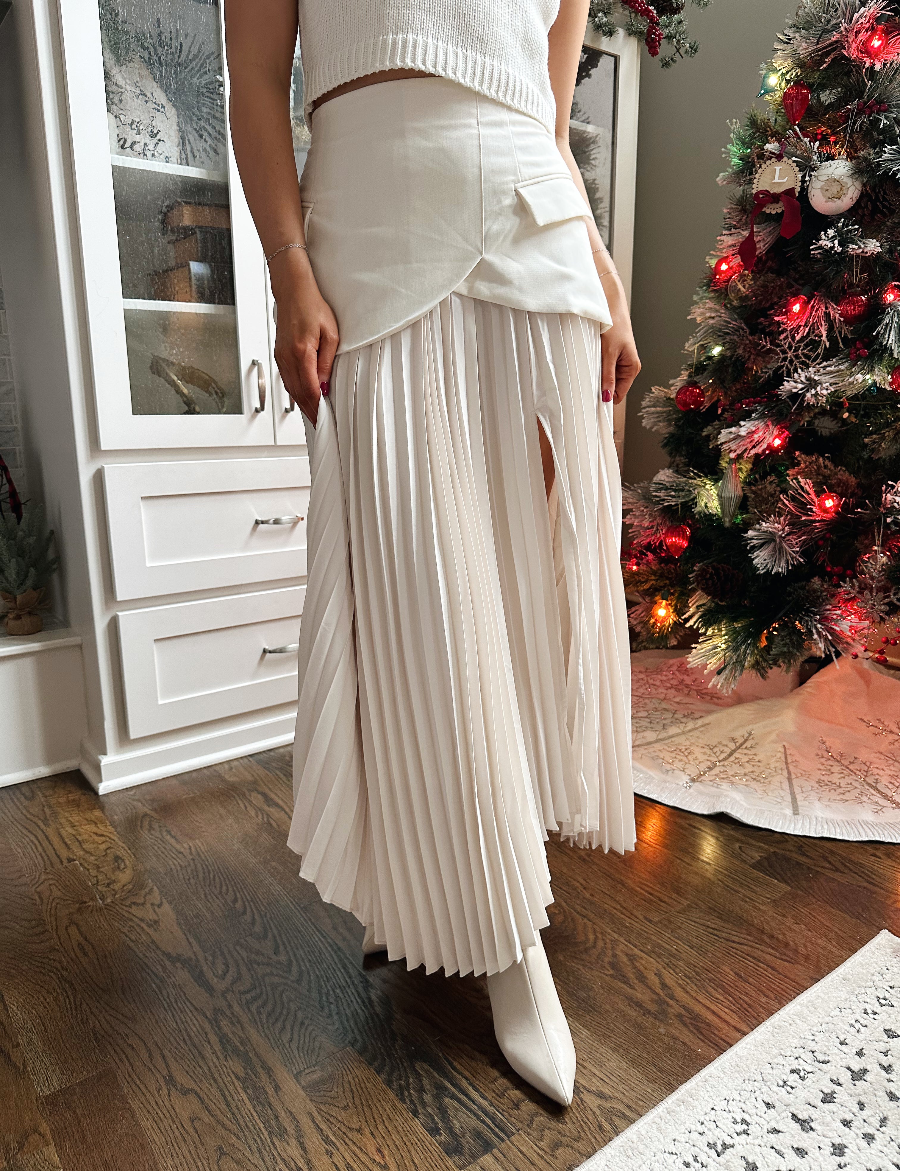 Woman wearing ivory asymmetrical maxi skirt with plated bottom.