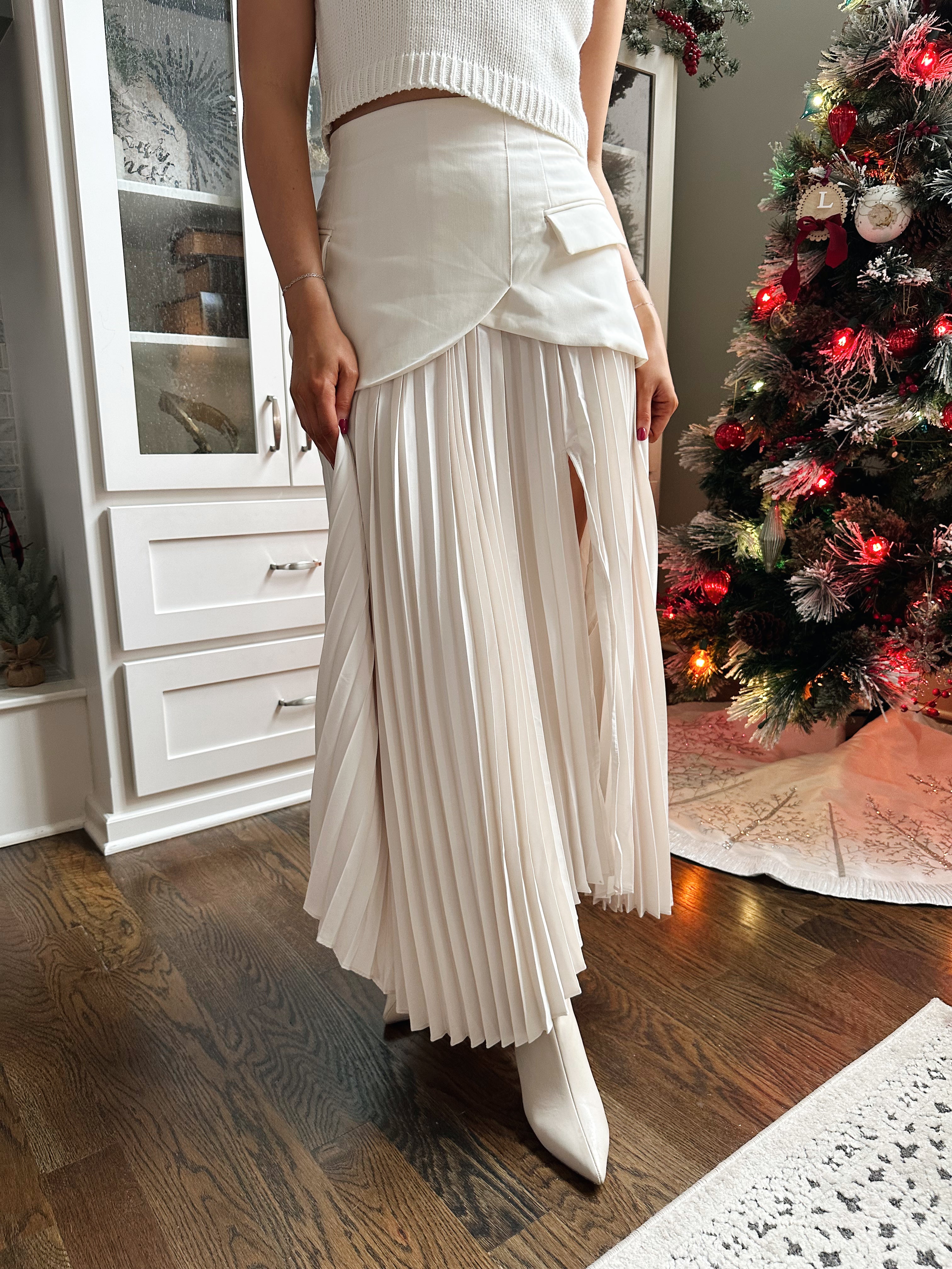 Woman wearing ivory asymmetrical maxi skirt with plated bottom.