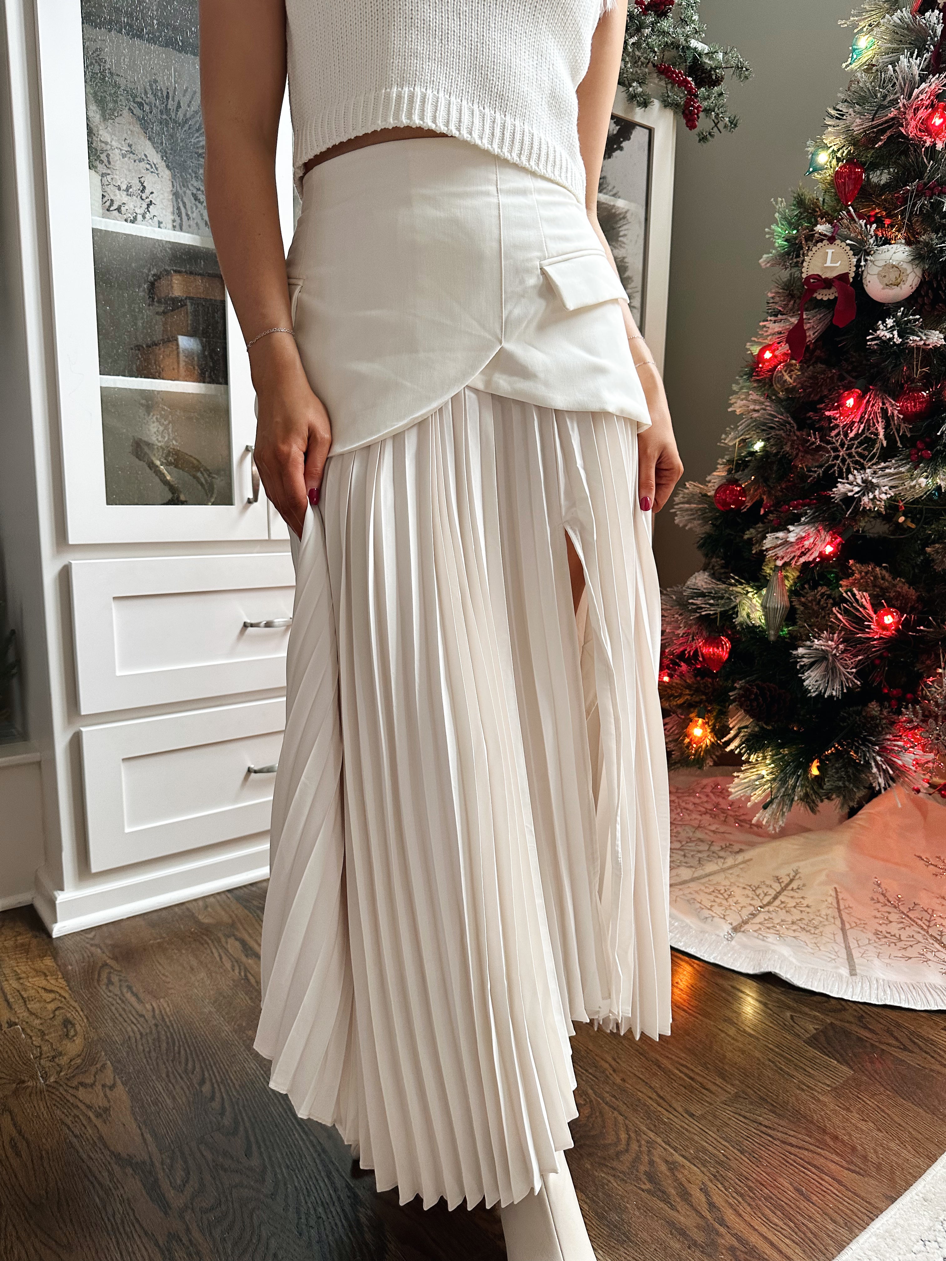 Woman wearing ivory asymmetrical maxi skirt with plated bottom.