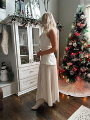 Woman wearing ivory asymmetrical maxi skirt with plated bottom.