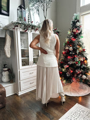 Woman wearing ivory asymmetrical maxi skirt with plated bottom.
