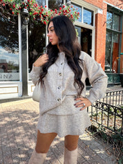 Woman wearing two piece sweater set with button down detailing, and built in shorts. 