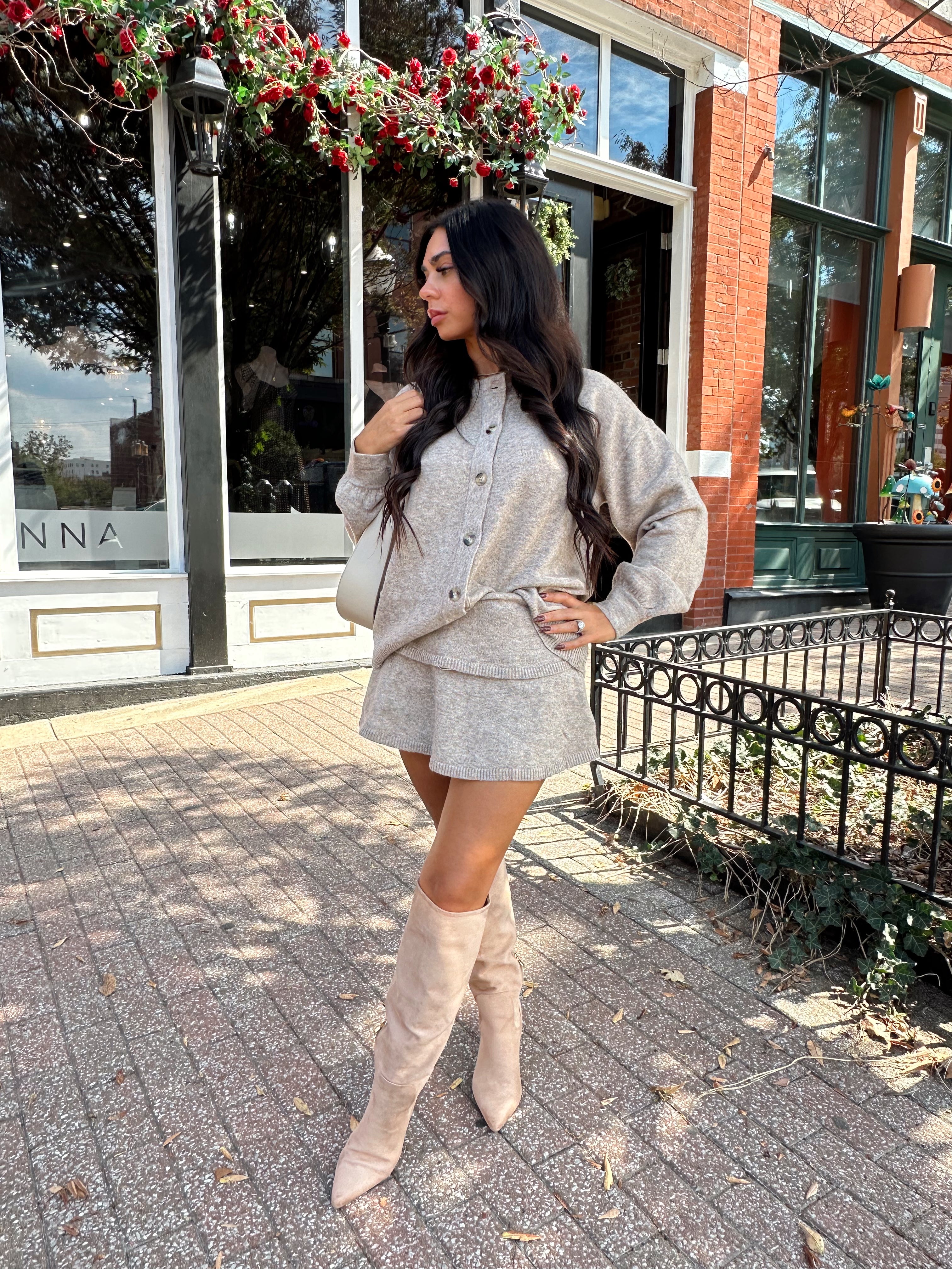 Woman wearing two piece sweater set with button down detailing, and built in shorts. 