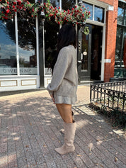 Woman wearing two piece sweater set with button down detailing, and built in shorts. 